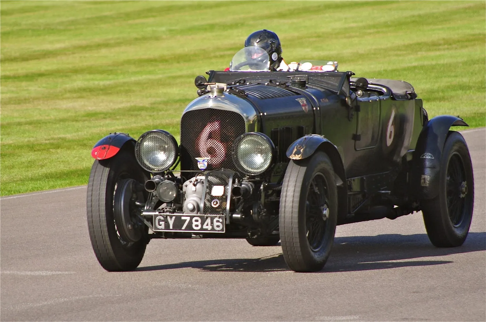 A green supercharged Bentley 4.5 Litre Blower racing on a circuit, front three-quarter view, UK registration GY 7846, race number 6