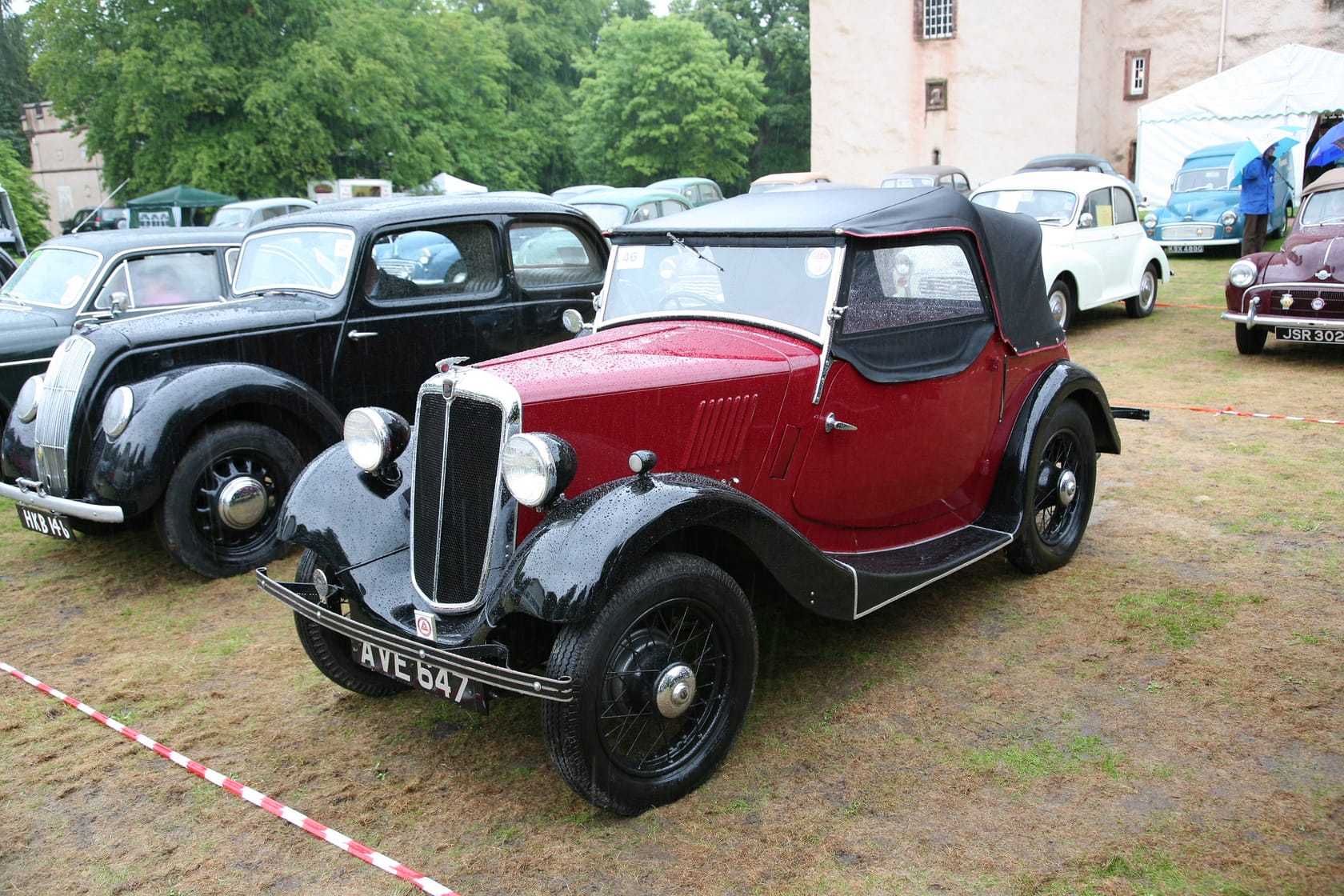 A maroon and black 1935 Morris Eight four-seat tourer at a classic car show, front three-quarter view