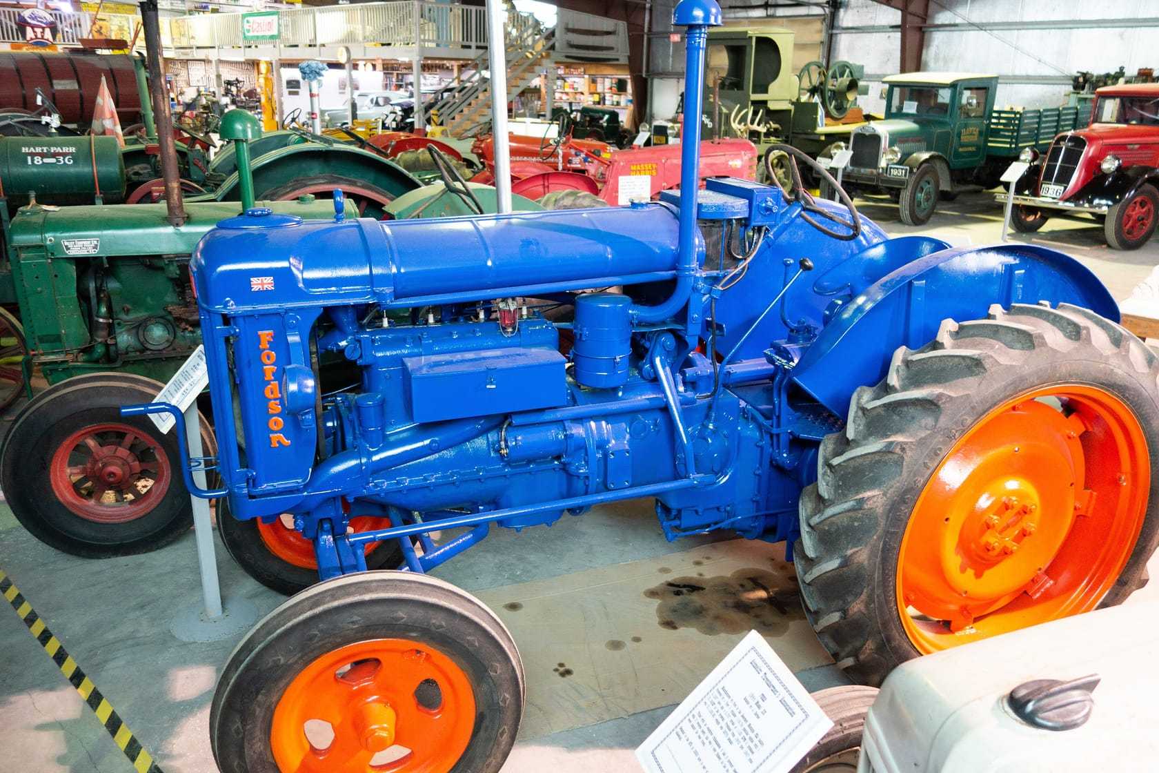 A restored blue and orange 1945 Fordson Major E27N displayed in a museum hall of vintage vehicles