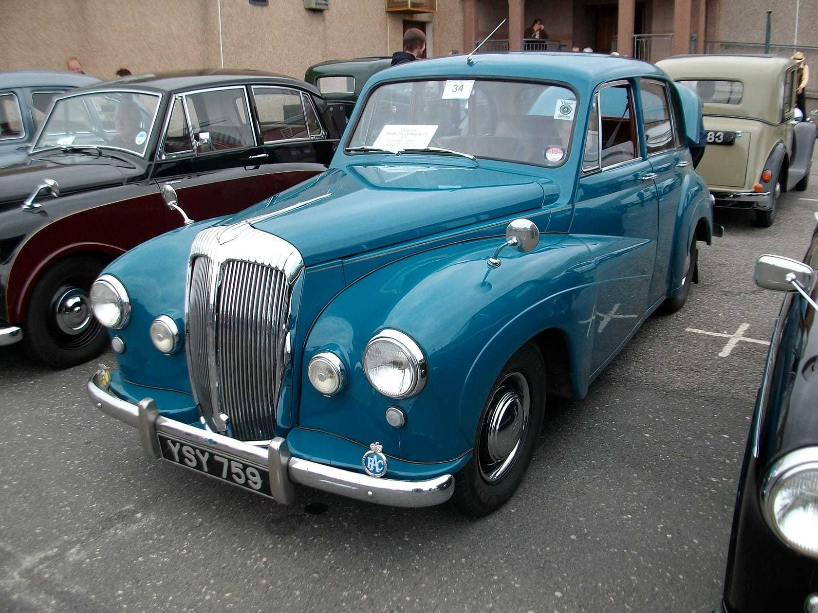 A blue 1953 Daimler Conquest saloon on grass at a classic car show, front three-quarter view