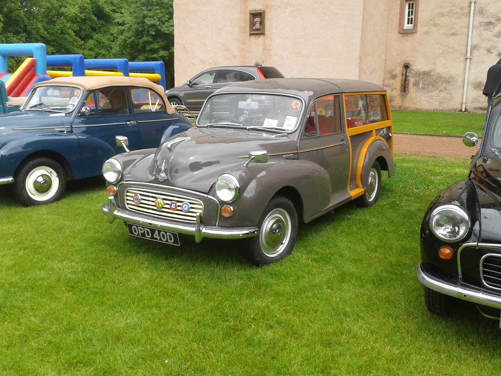 A maroon 1966 Morris Minor Traveller estate with ash wood rear framing parked on grass at a show