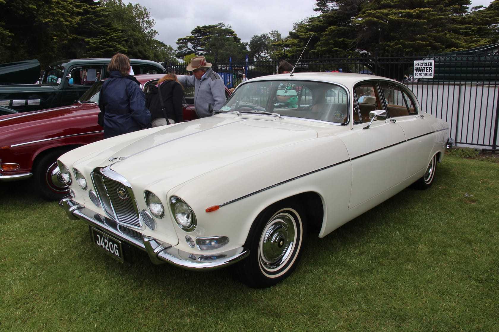A white 1968 Jaguar 420G saloon at a classic car show, front three-quarter view with whitewall tyres