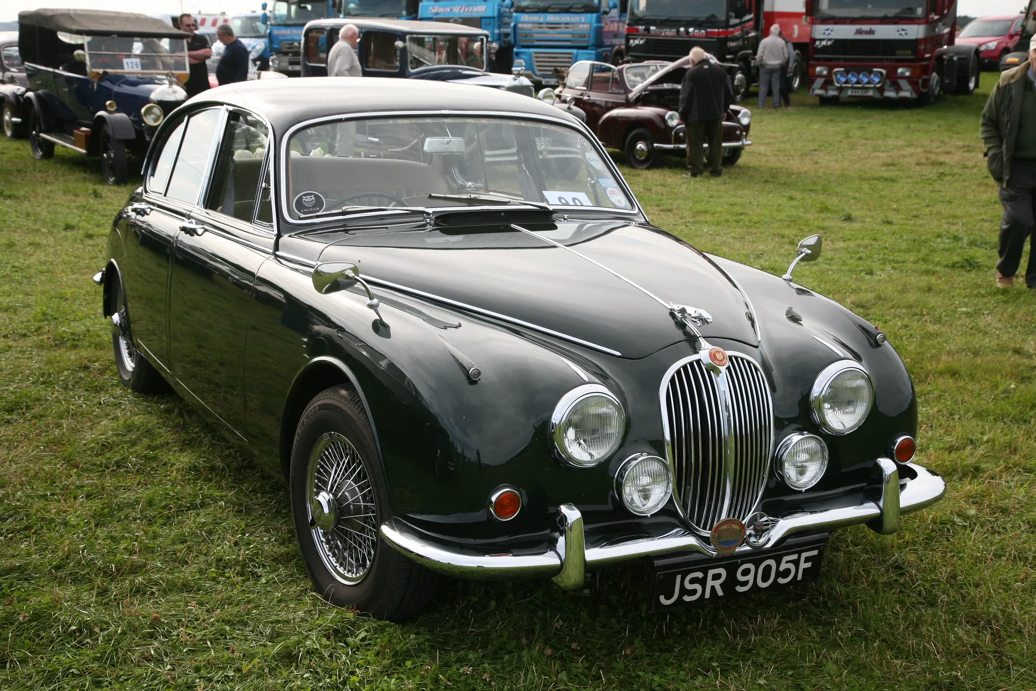 A dark green Jaguar Mk2 saloon, front three-quarter view, on grass at a classic car show