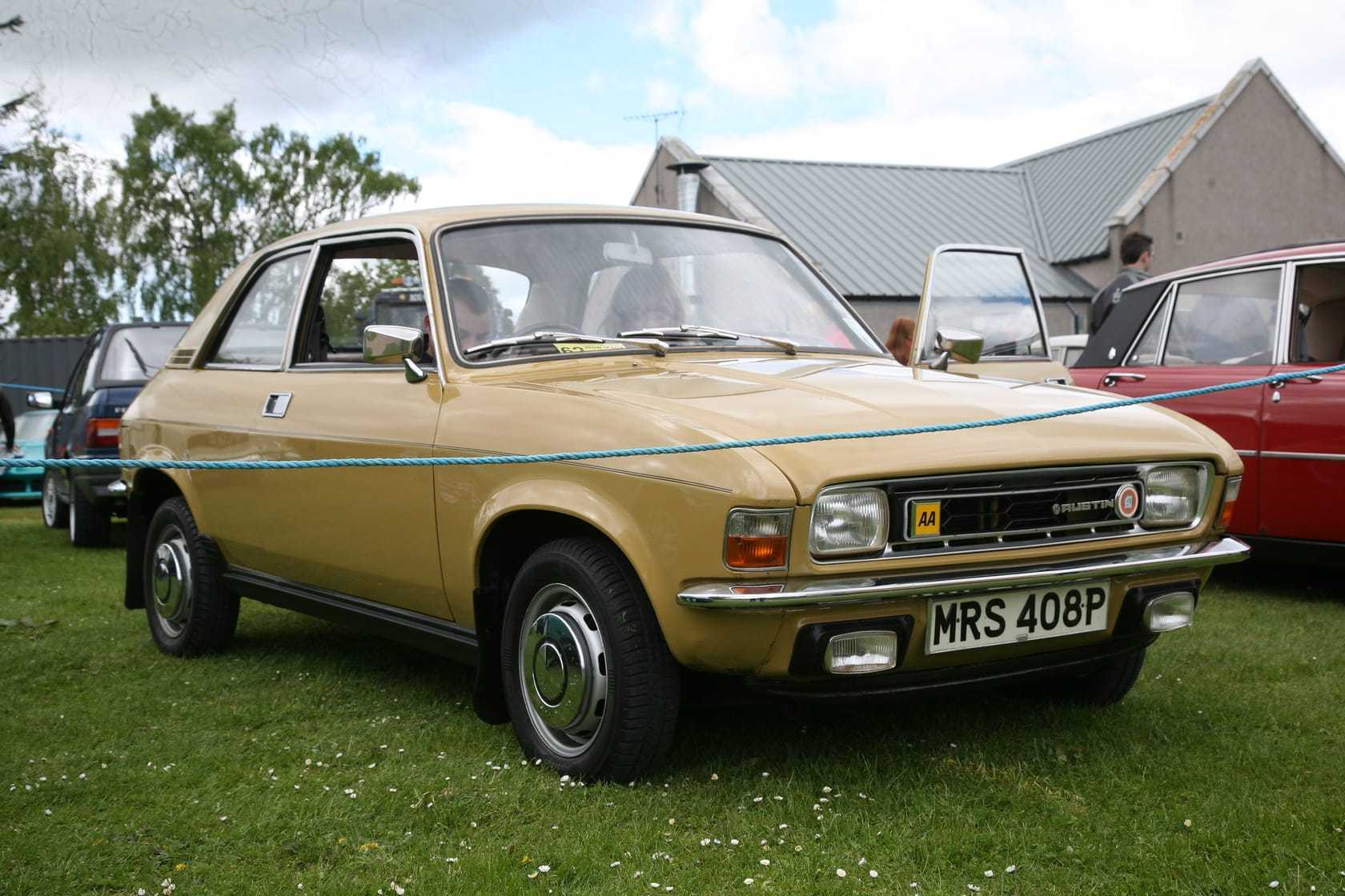 A mustard yellow 1976 Austin Allegro 1300 at a classic car show, front three-quarter view, UK registration MRS 408P