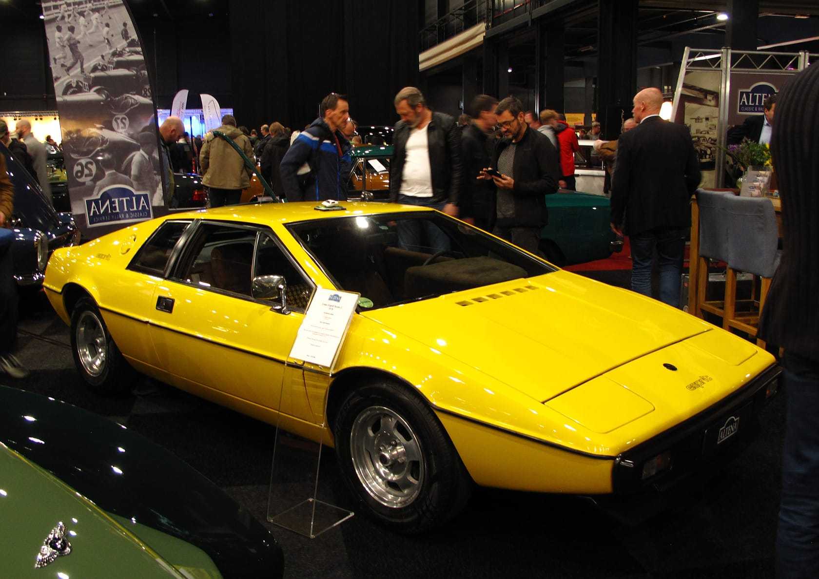 A yellow 1978 Lotus Esprit S1 displayed at an indoor classic car show