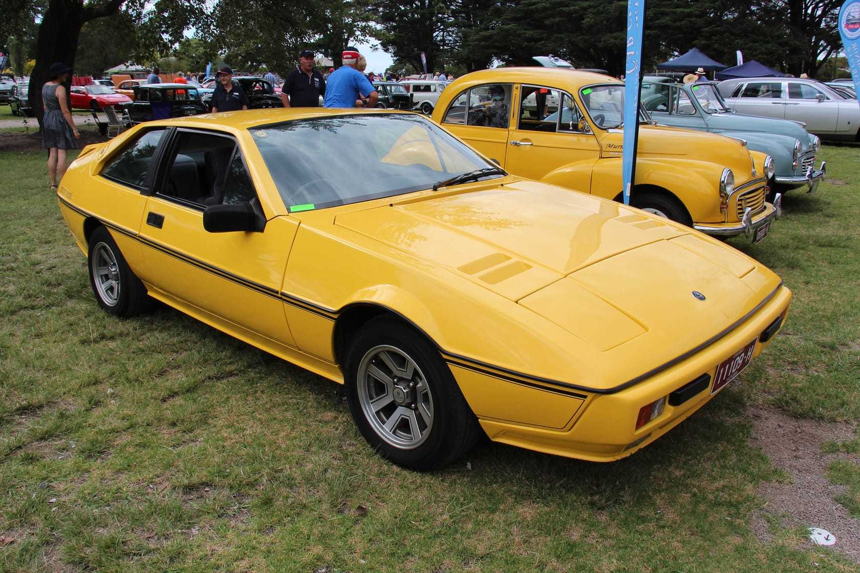 A yellow 1984 Lotus Excel at a classic car show, front three-quarter view