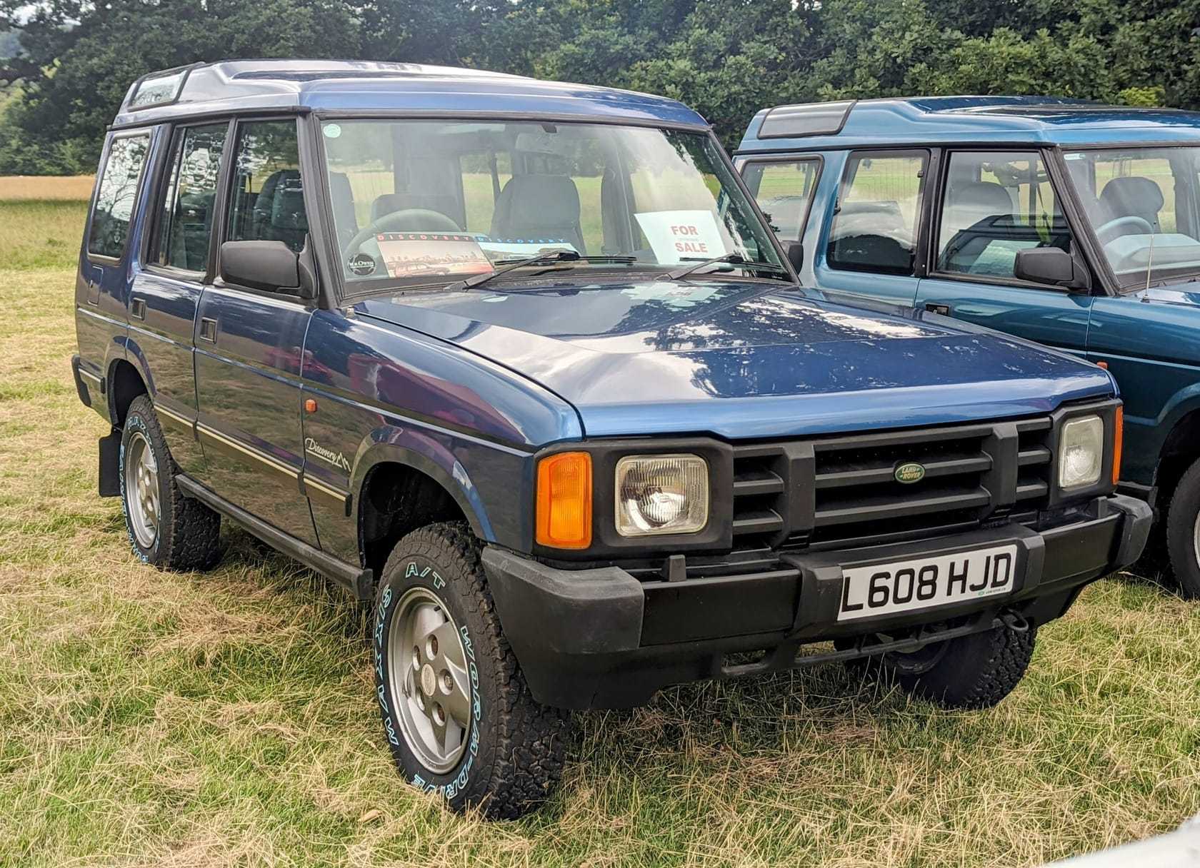 A blue 1994 Land Rover Discovery 1 three-door with a for-sale sheet in the window on a show field