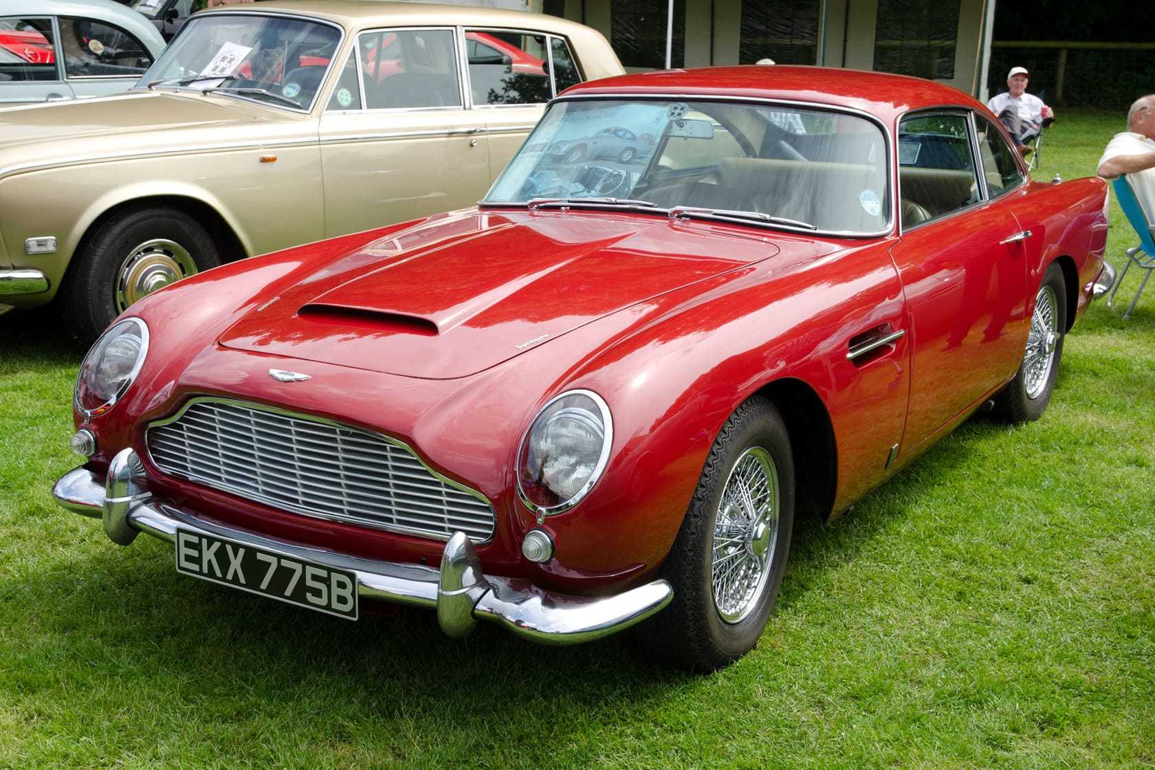 A red Aston Martin DB5 with UK registration EKX 775B at an outdoor classic car show