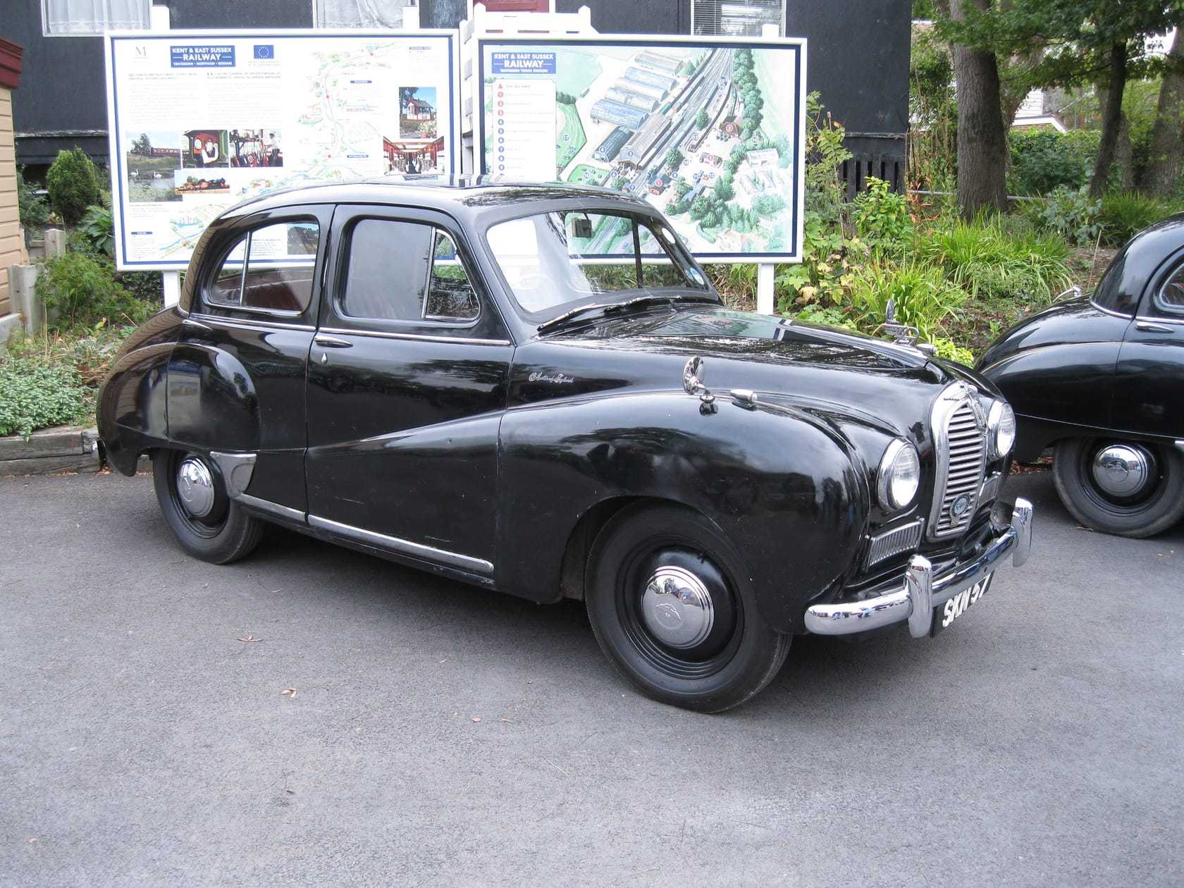 A black Austin A40 Somerset saloon at an outdoor classic car gathering, front three-quarter view