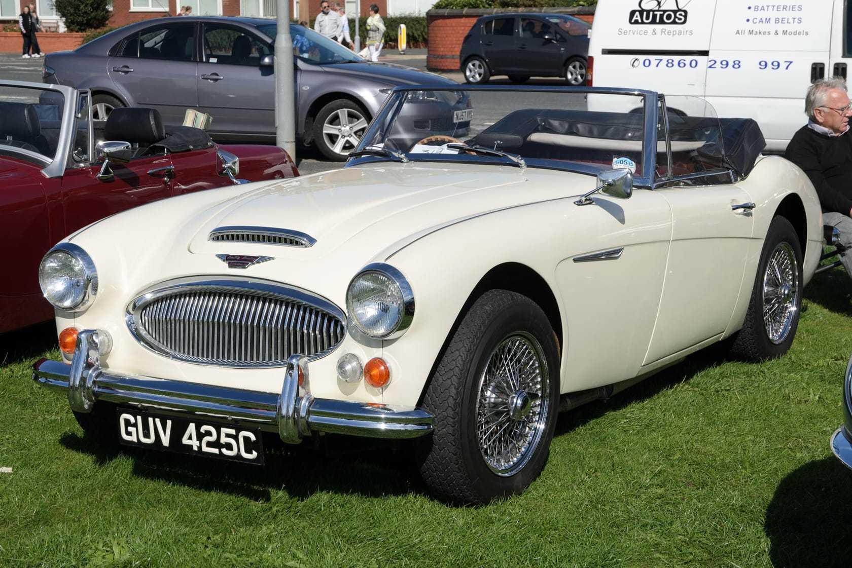 A cream 1965 Austin-Healey 3000 Mk III with wire wheels and a UK registration, parked on a show field with its hood down