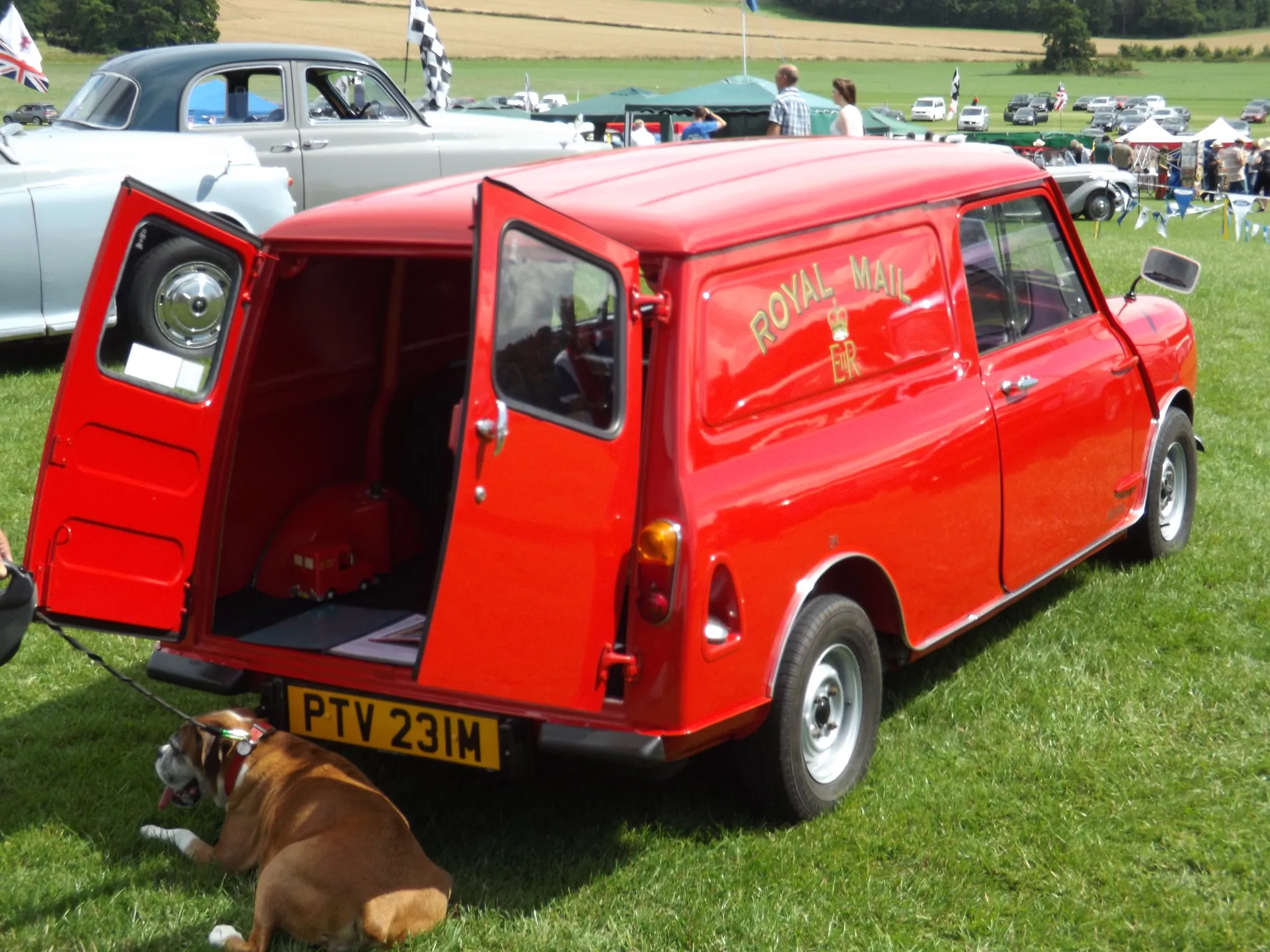 A red Mini Van in Royal Mail livery with its rear doors open, at a show
