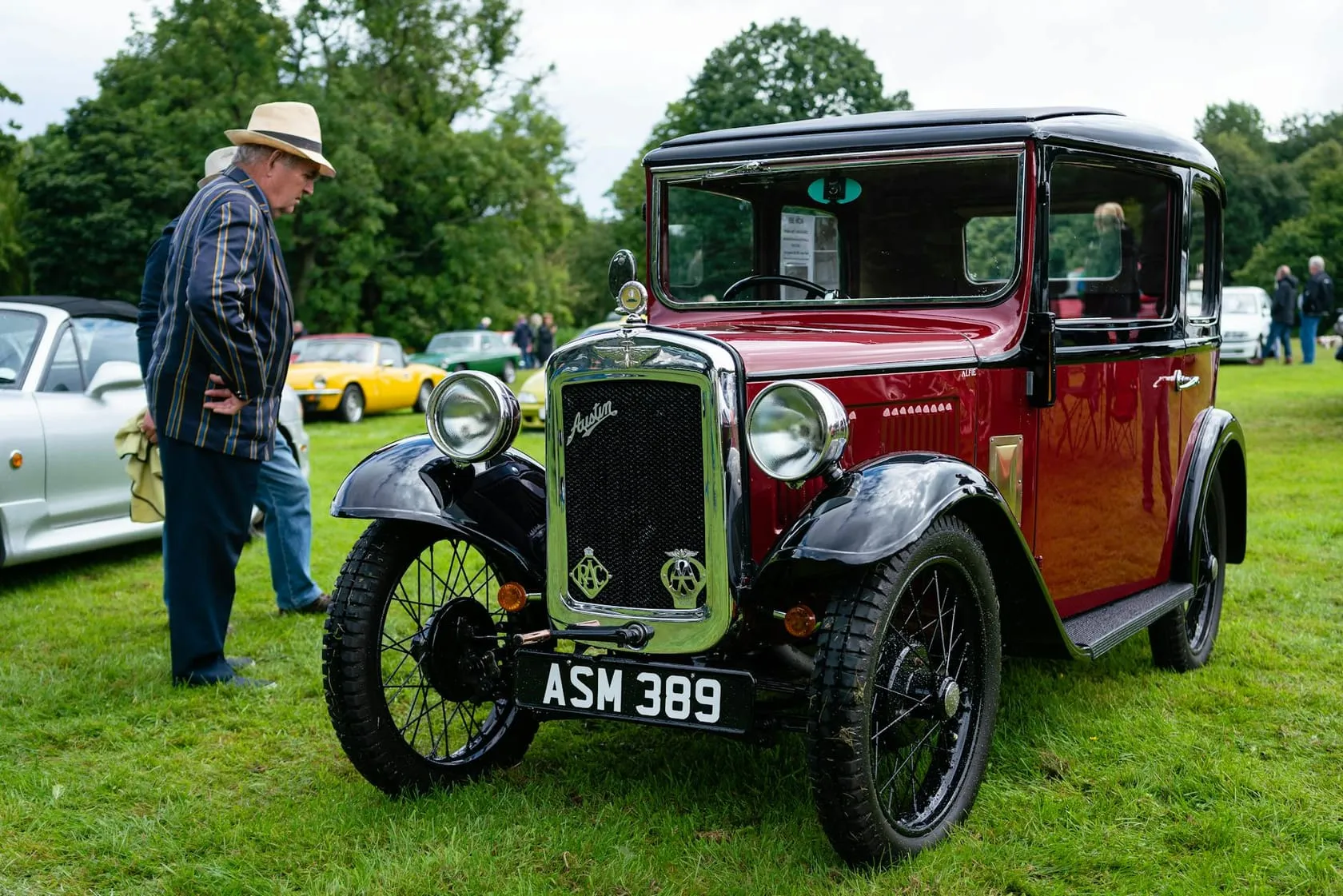 A maroon Austin Seven Ruby saloon at a show, front three-quarter view, UK registration ASM 389