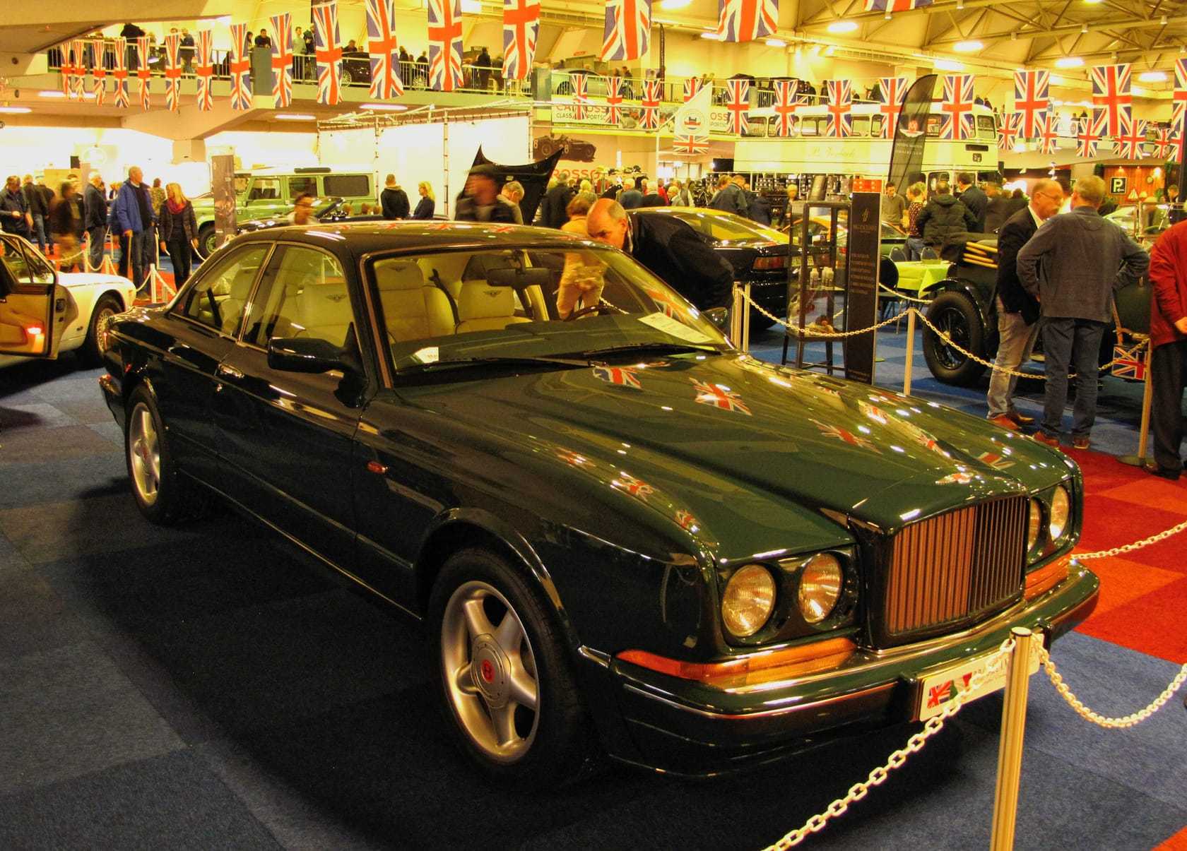 A dark green Bentley Continental R at an indoor classic car show
