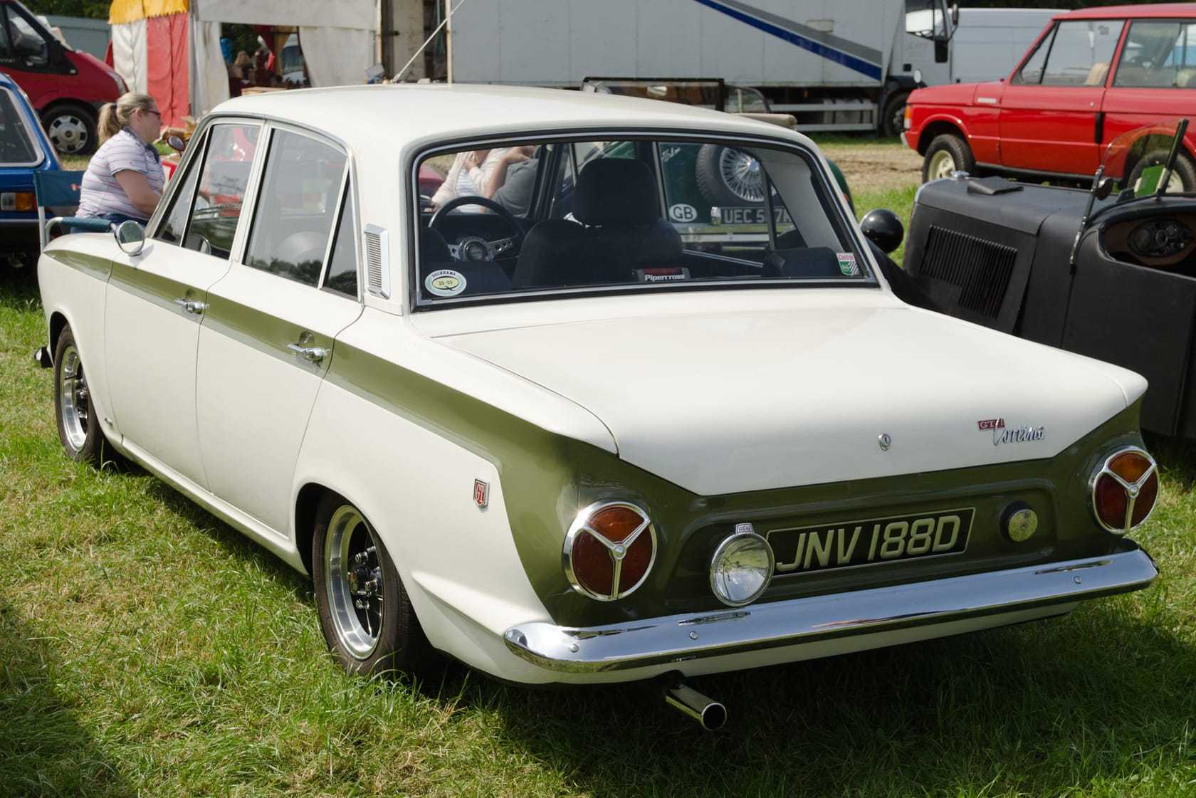 The rear of a white and green 1966 Ford Cortina Mk1 GT with a UK registration on a show field