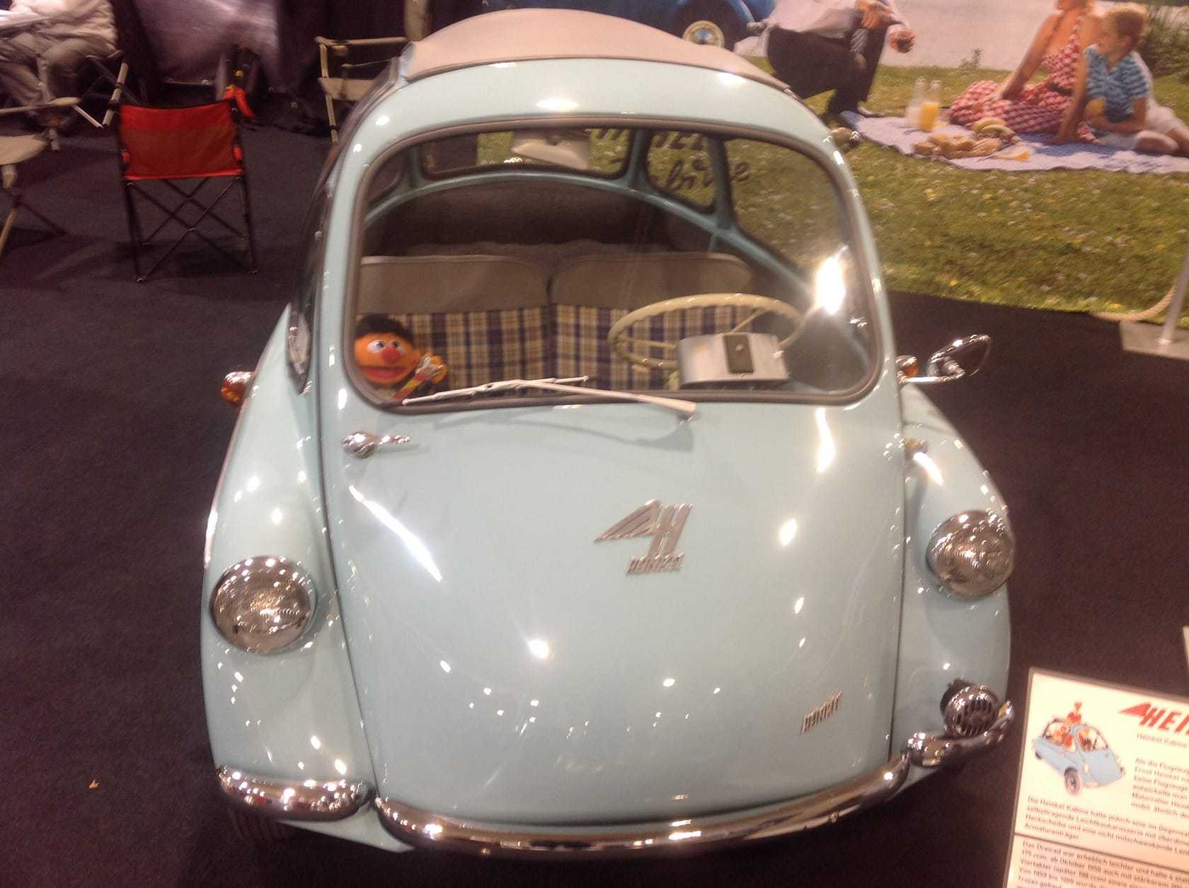 A pale blue Heinkel Kabine bubble car displayed indoors, front view showing the full-width front door
