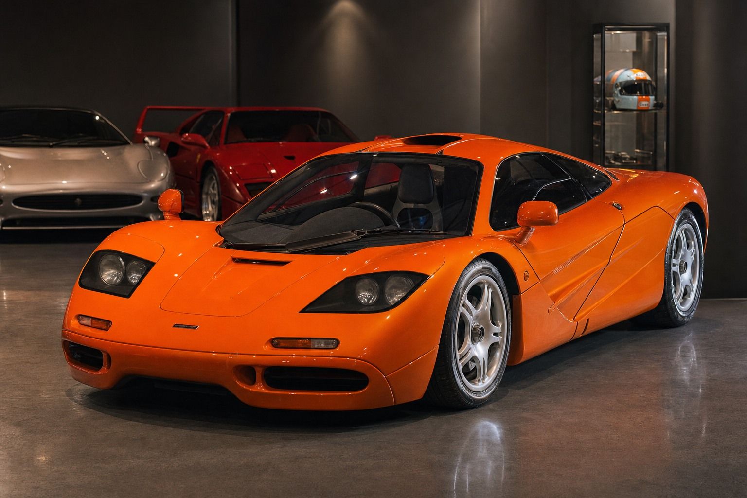 An orange McLaren F1 displayed in a private collection alongside a Ferrari F40