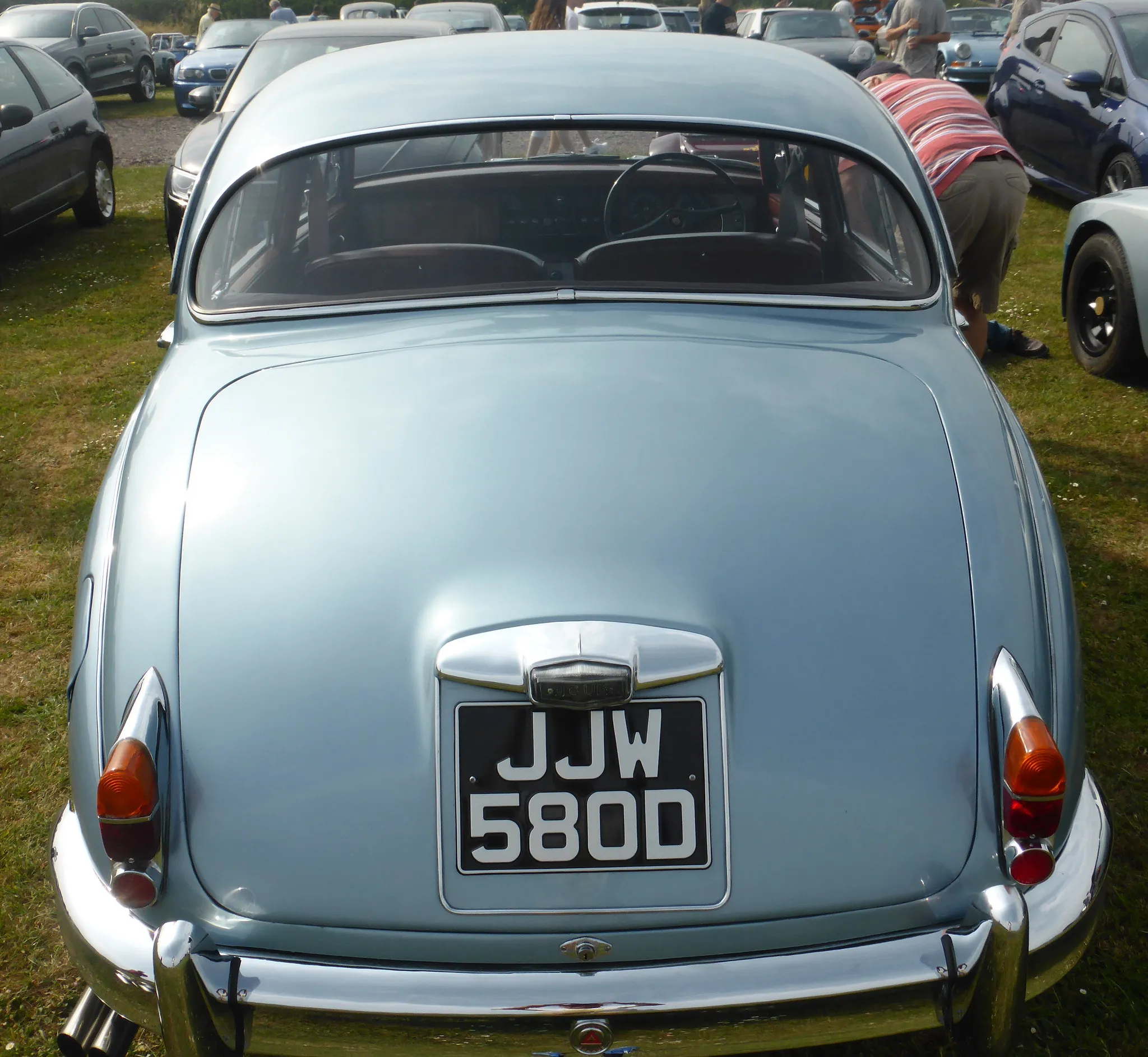 The rear of a light blue Jaguar Mk2 saloon at a show, showing the black-on-silver number plate 'JJW 580D'