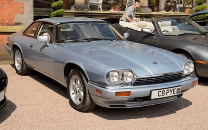 A silver-blue 1995 Jaguar XJS 4.0 coupé with a UK registration parked at a show, front three-quarter view