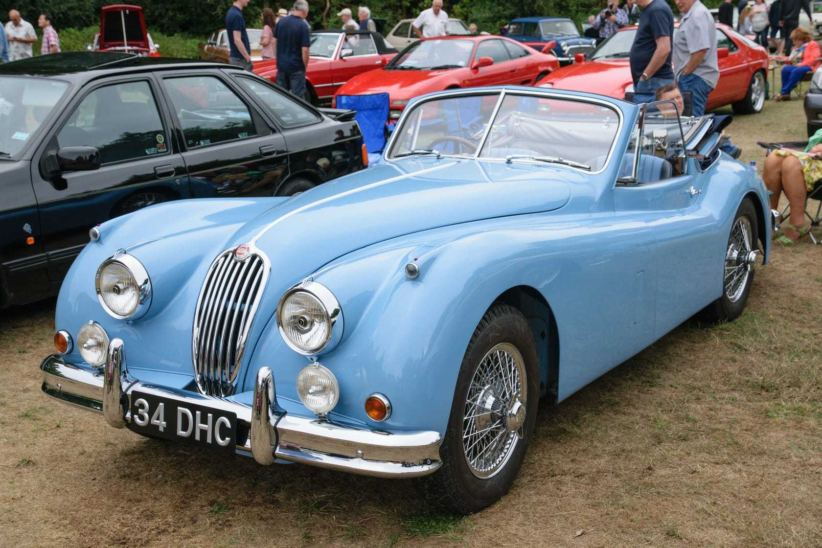 A light blue 1955 Jaguar XK140 drophead coupé with wire wheels and a UK registration at a show