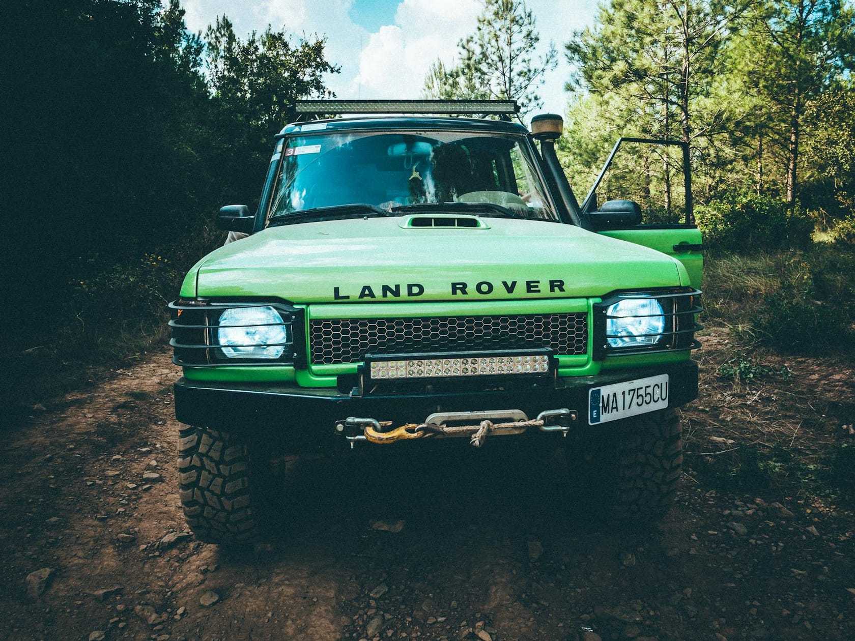 A green Land Rover Discovery 1 on an off-road track among trees