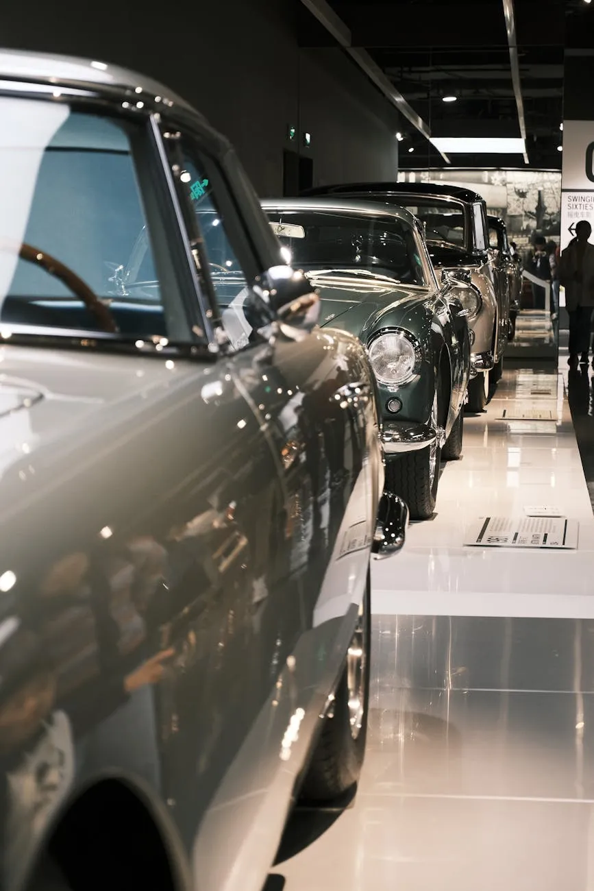 A line of classic cars displayed end-on in a darkened museum hall, chrome grilles and headlamps catching the light