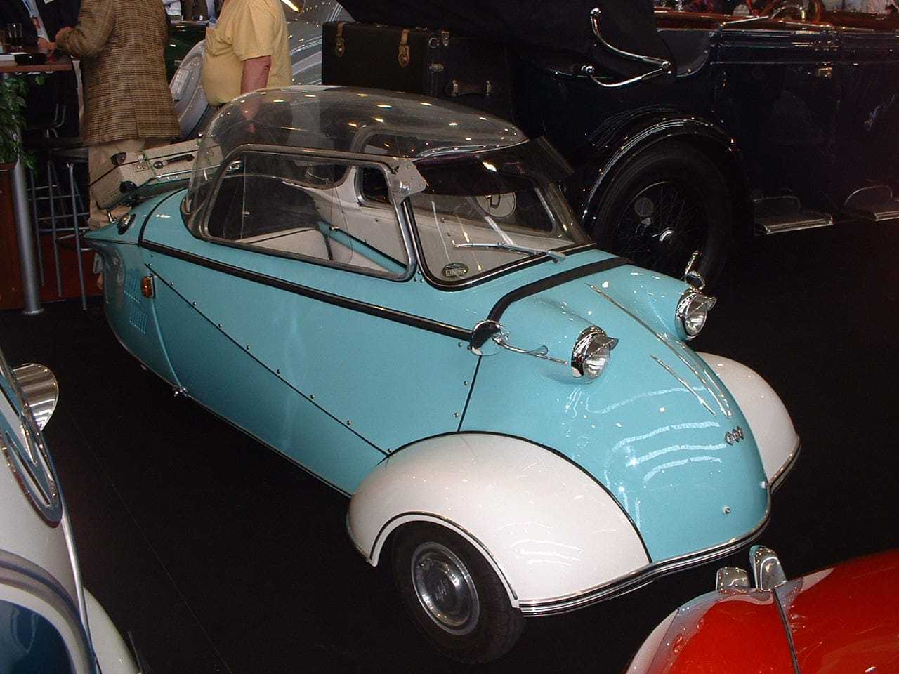 A turquoise and white Messerschmitt KR200 with its bubble canopy closed, displayed indoors