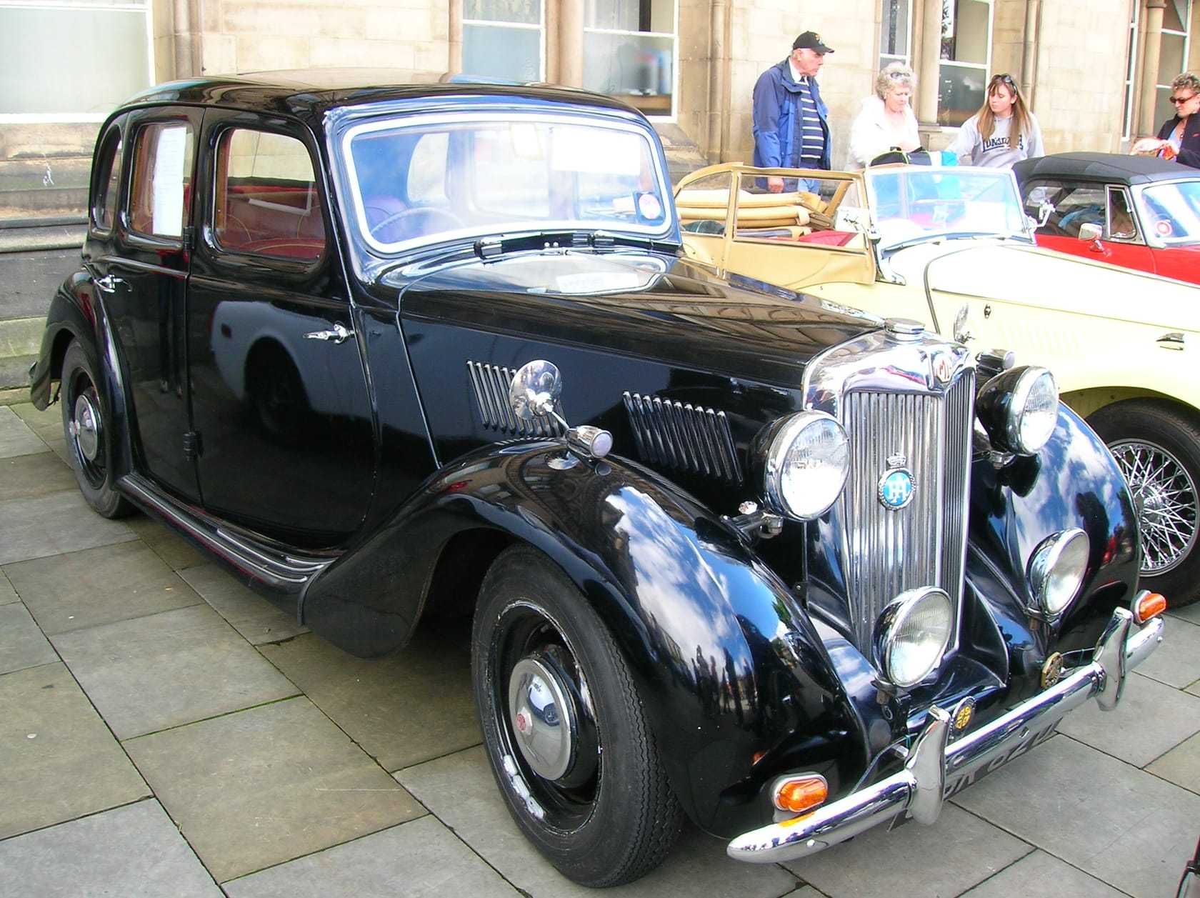 A green MG saloon of the 1950s displayed at a classic car show with its bonnet closed, viewed from the front
