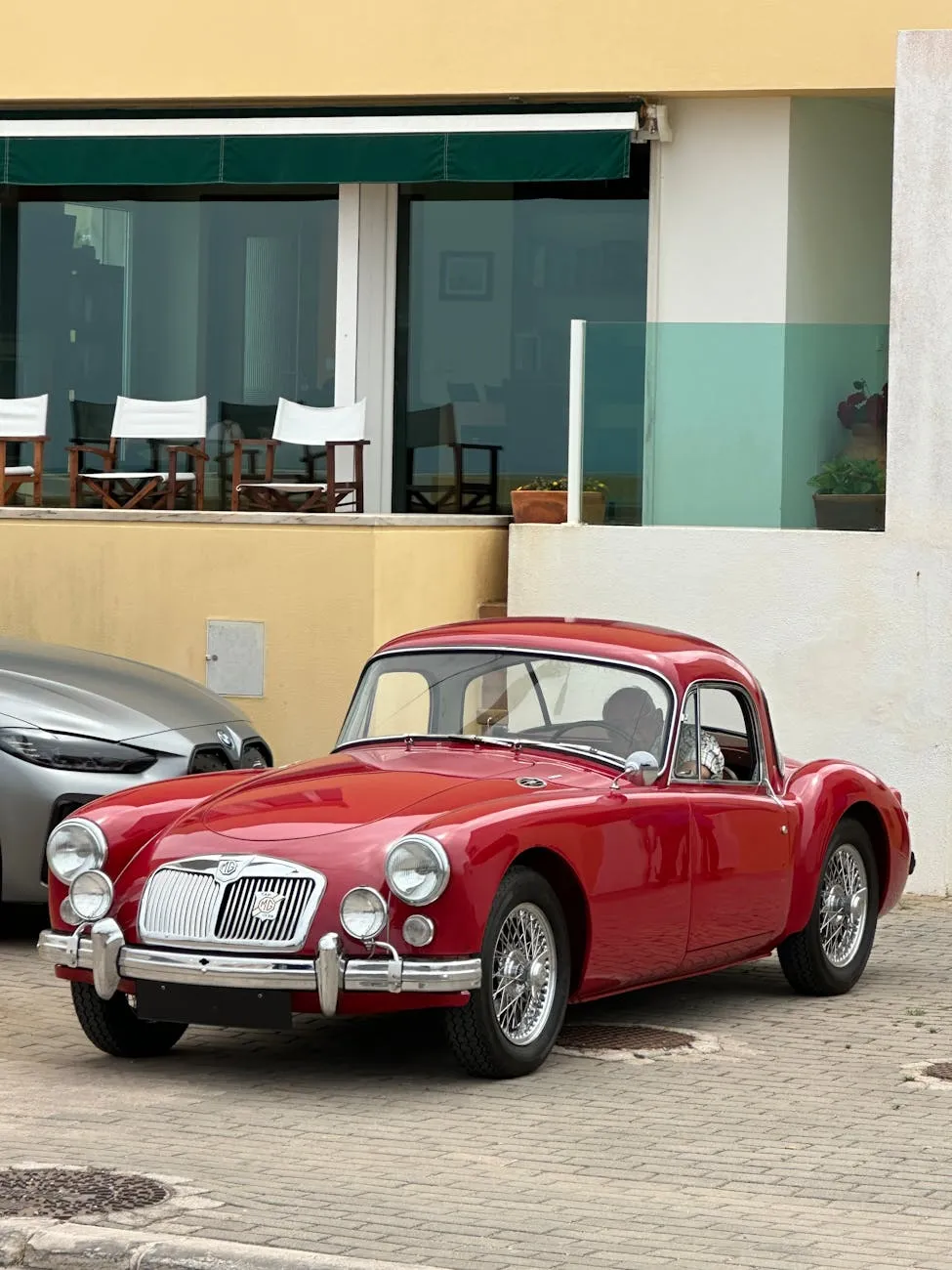 A red MG MGA fixed-head coupe, front three-quarter view on a street