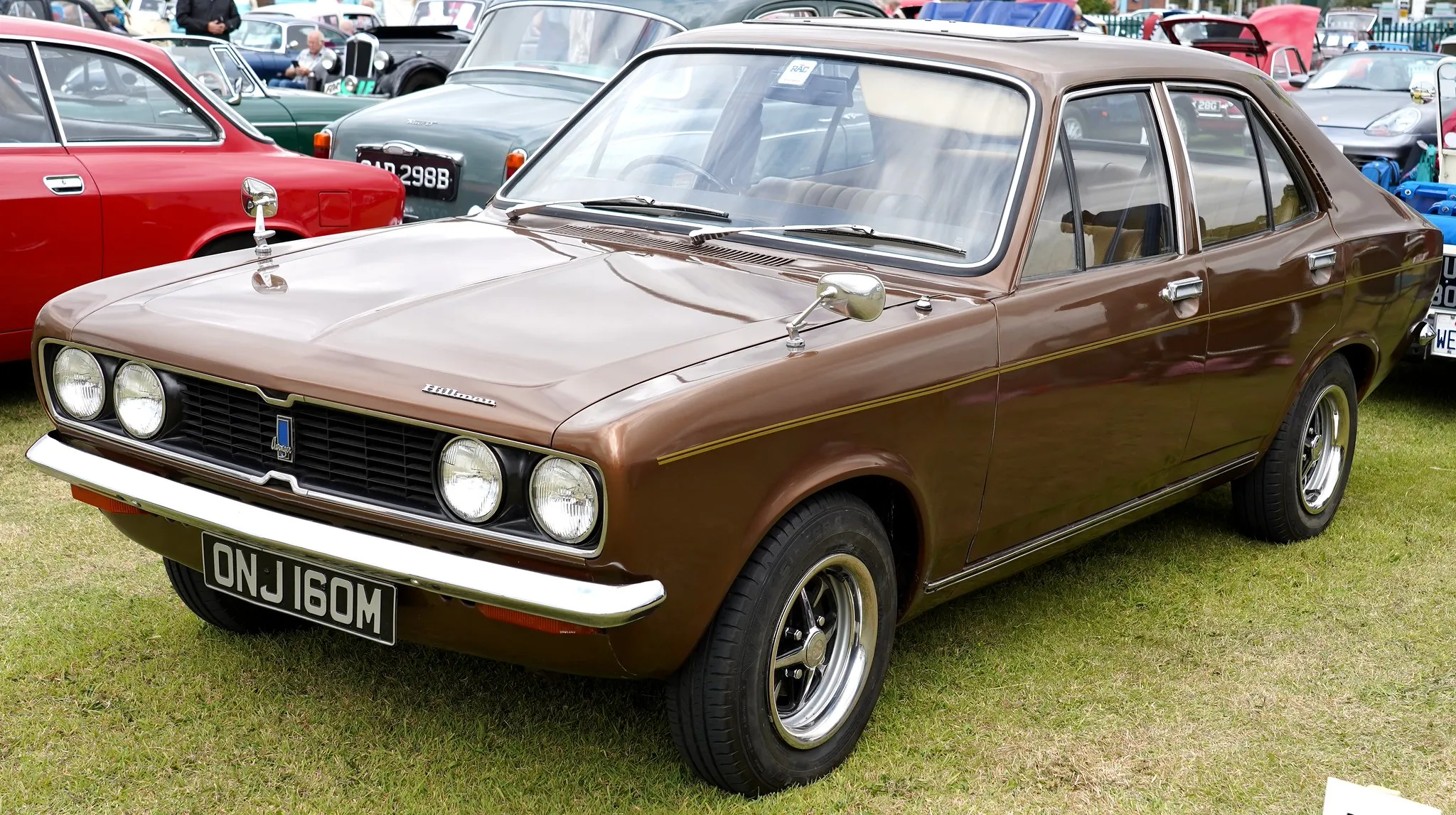 A brown metallic Hillman Avenger four-door saloon (M registration, 1973-74), front three-quarter view at an outdoor classic car show
