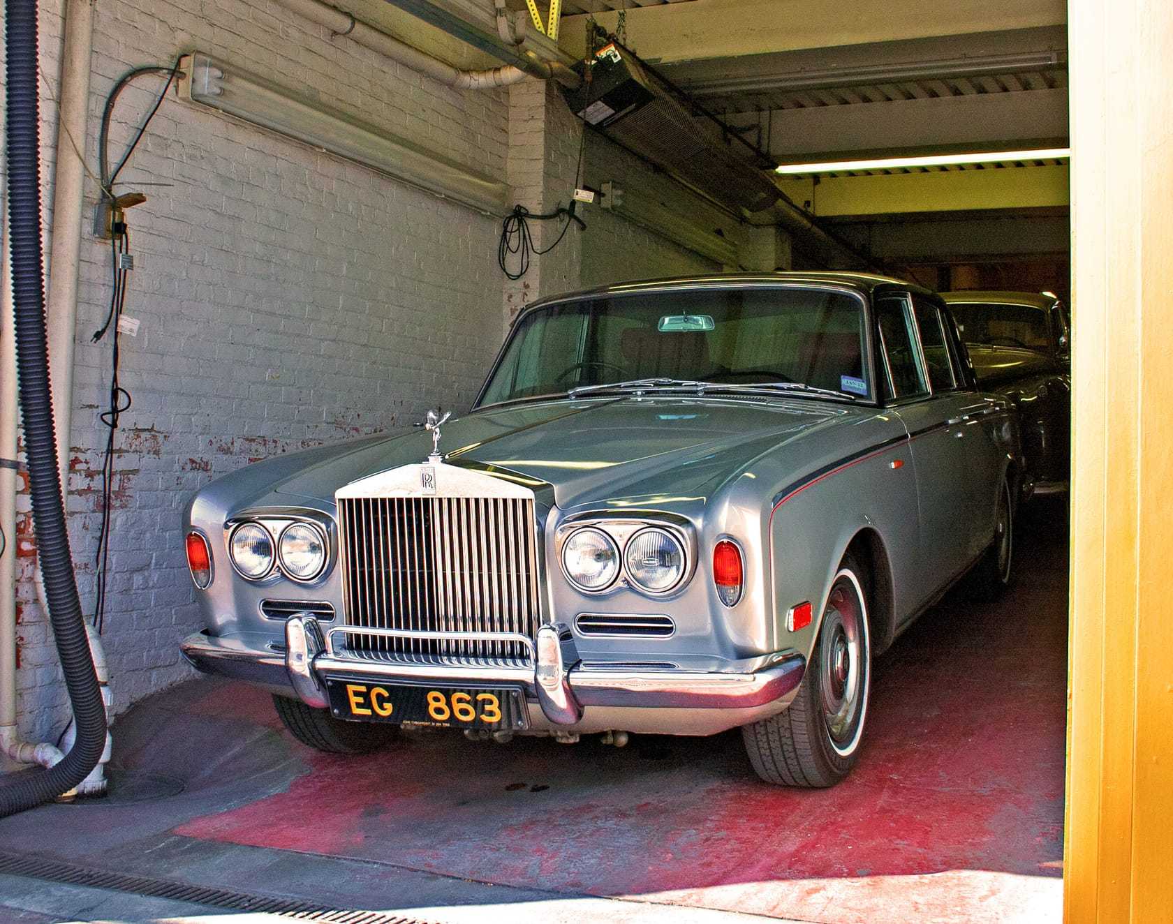 A silver Rolls-Royce Silver Shadow saloon in a garage wearing its original British registration plate