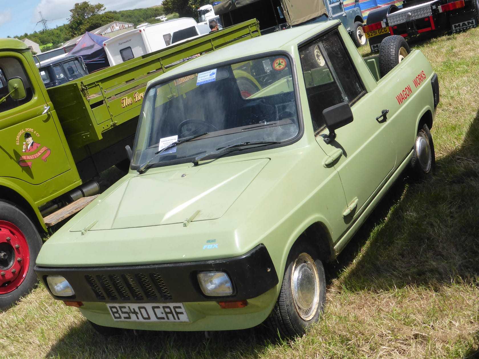 A green 1985 Reliant Fox pickup at a vehicle show, front three-quarter view, UK registration B540 CAF