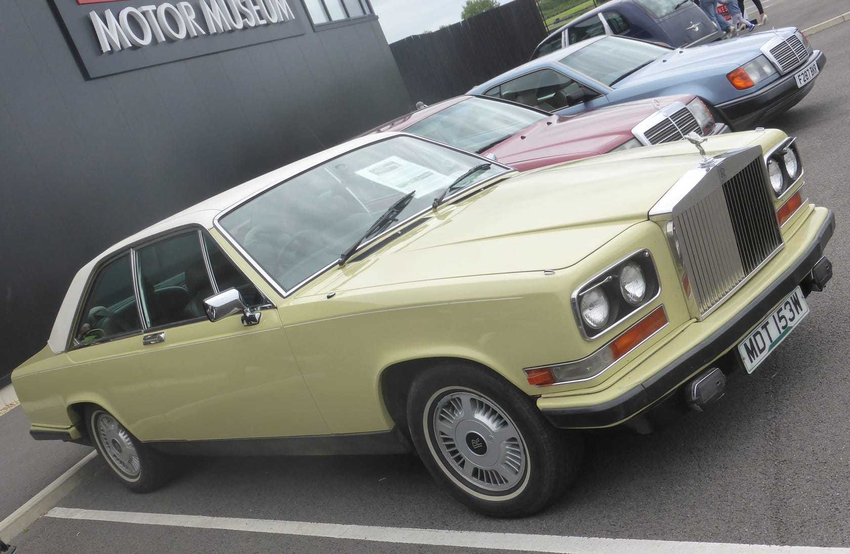 A cream Rolls-Royce Camargue outside a motor museum