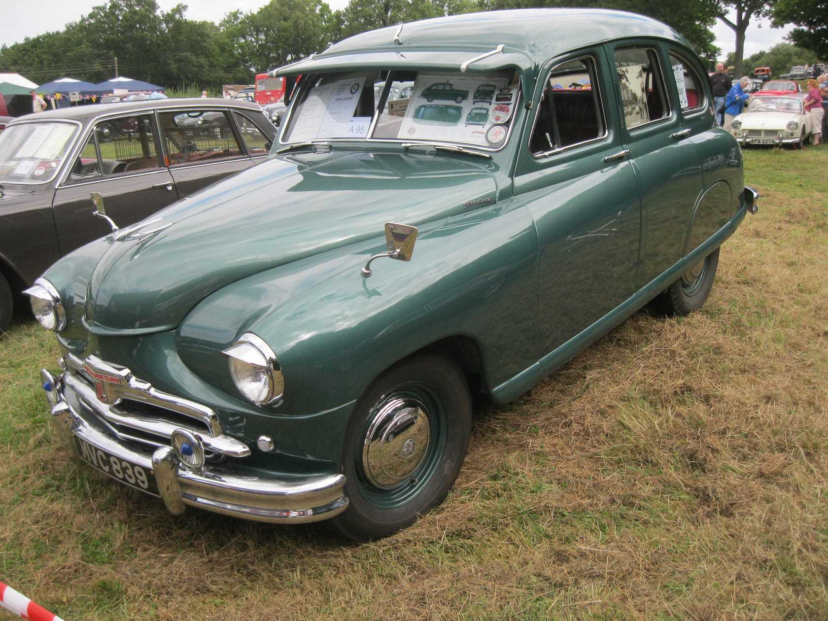 A green Standard Vanguard Phase I on grass at a show, front three-quarter view showing the beetle-back styling