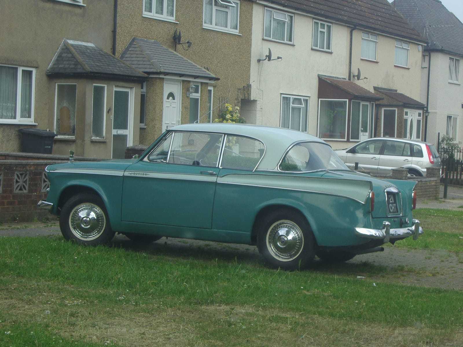 A green and cream two-tone 1958 Sunbeam Rapier parked on a suburban grass verge, side view