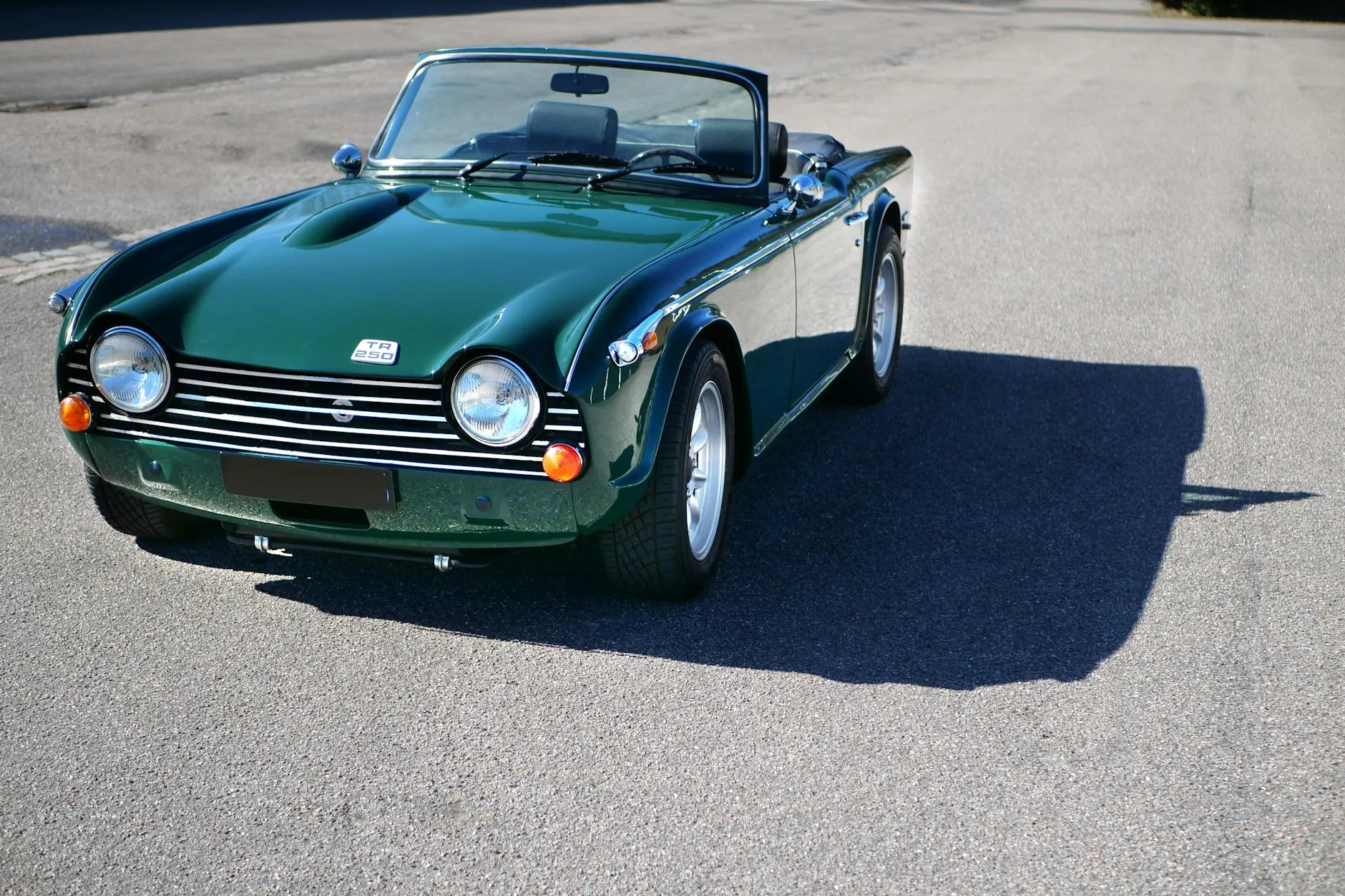 A British Racing Green Triumph TR4 roadster with the top down, front three-quarter view