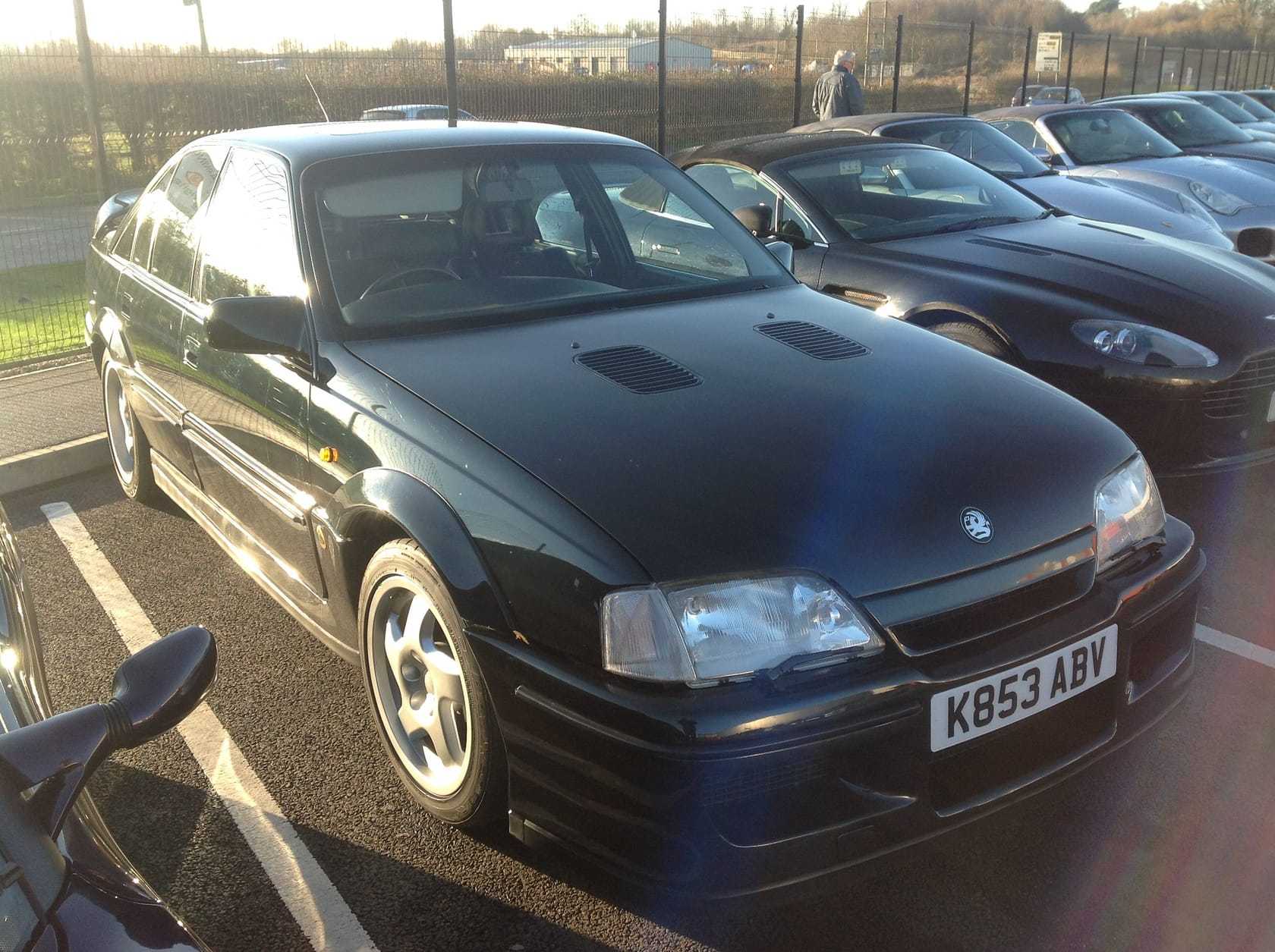 A dark green Lotus Carlton saloon in a car park, front three-quarter view, UK registration K853 ABV
