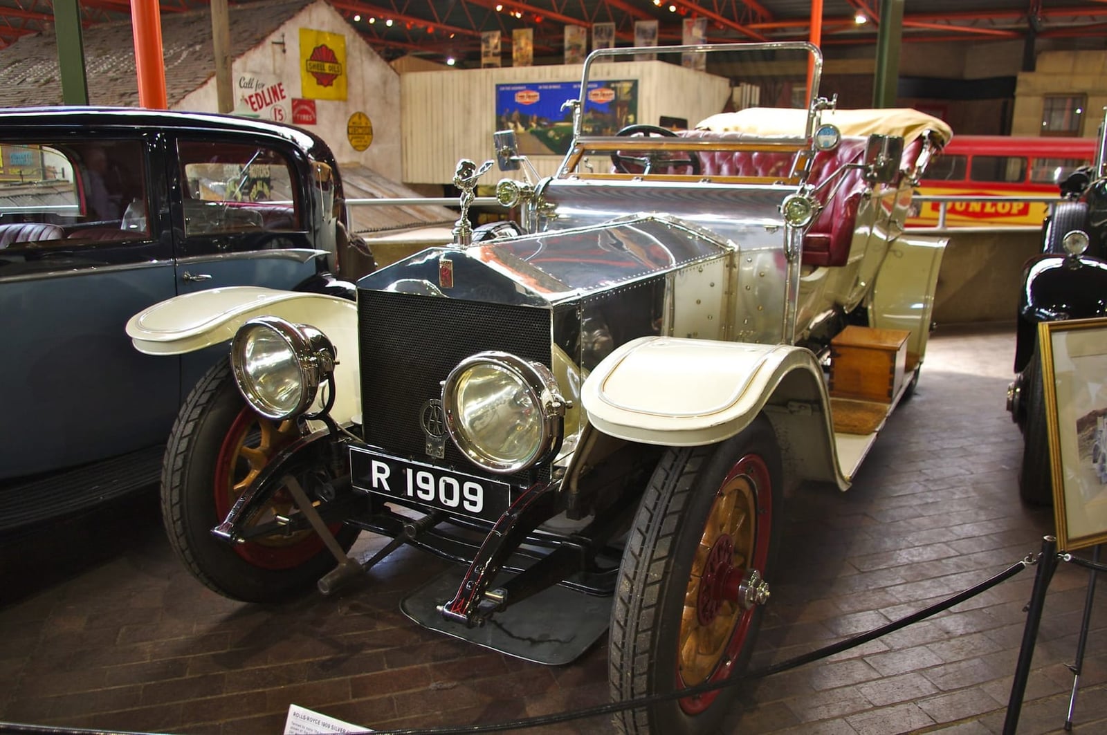 A silver 1909 Rolls-Royce Silver Ghost with registration R 1909 displayed in a museum