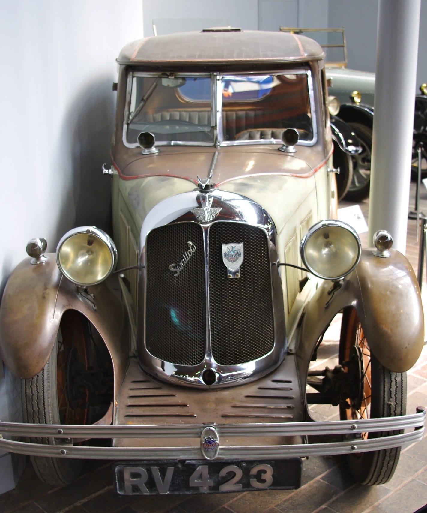 An unrestored 1931 Austin Seven Swallow with a cream and brown two-tone body and a UK registration in a museum