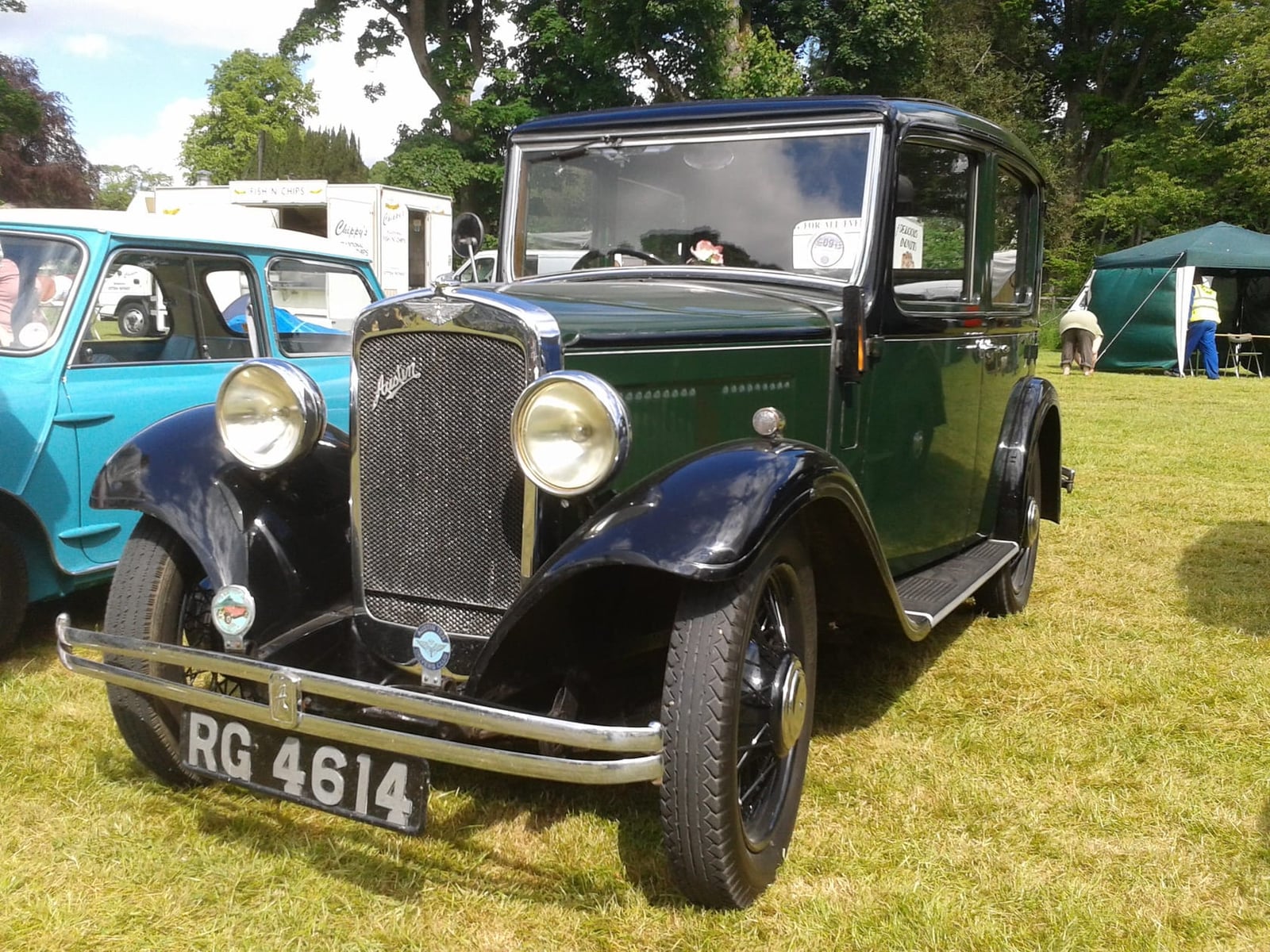 A green 1934 Austin Ten-Four saloon on grass at a vintage rally, front three-quarter view, UK registration RG 4614