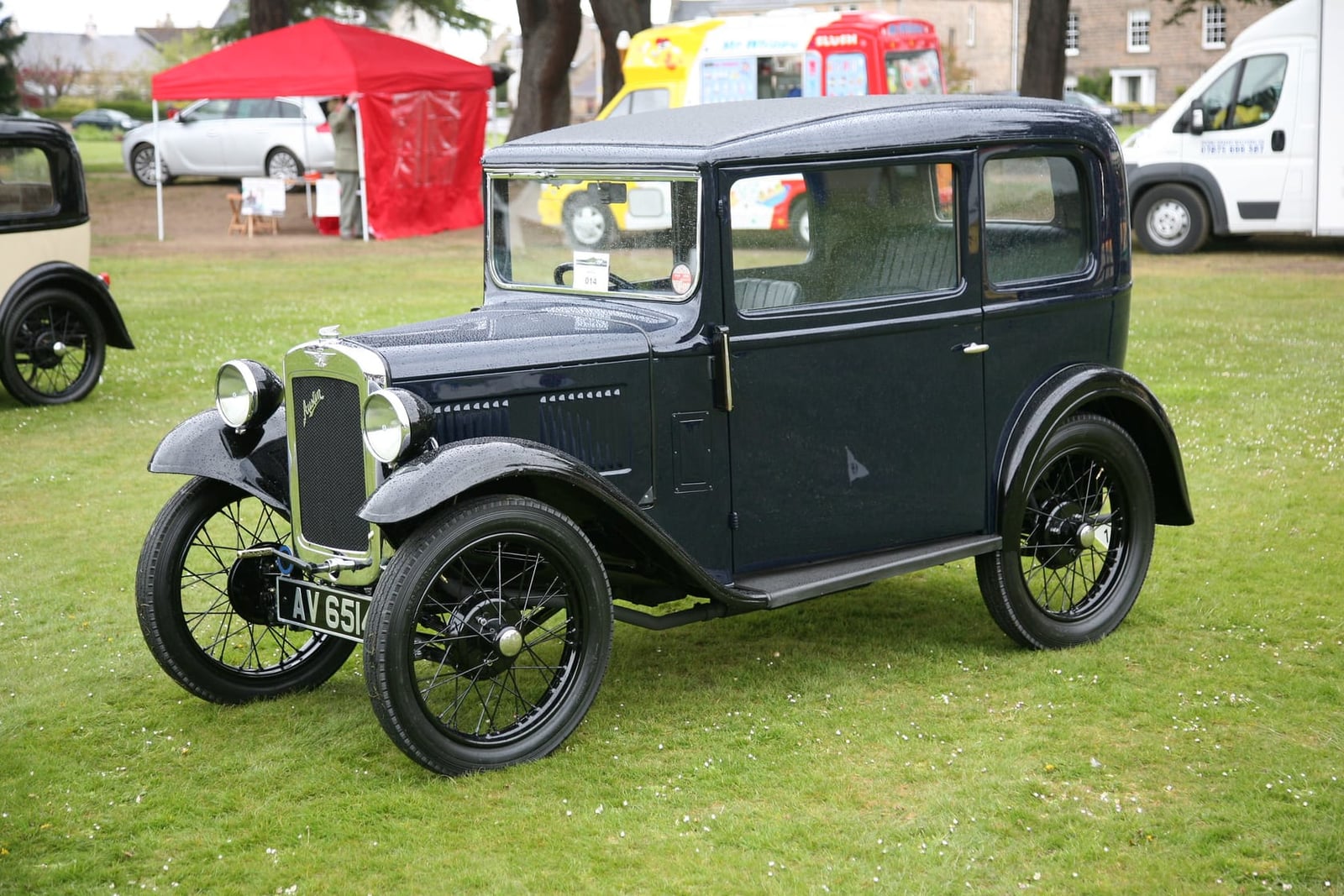 A dark blue 1934 Austin Seven box saloon with a UK registration on a show field