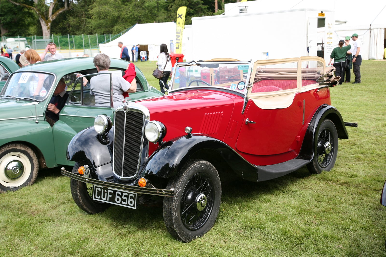 A red and black Morris Eight tourer of 1936 at a show, front three-quarter view, UK registration CUF 656