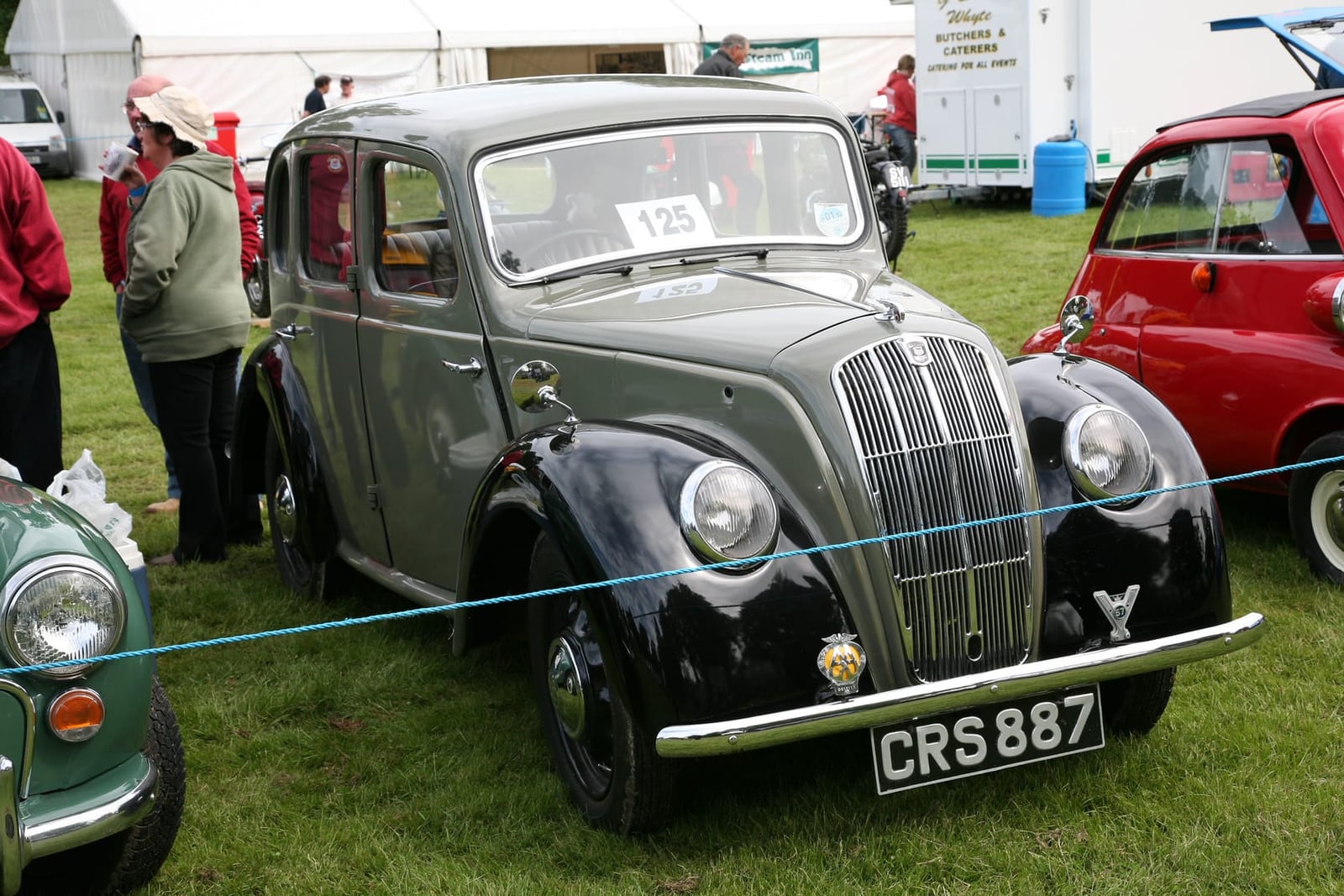 A green and black 1947 Morris Eight Series E saloon on grass at a classic vehicle show, front three-quarter view, UK registration CRS 887