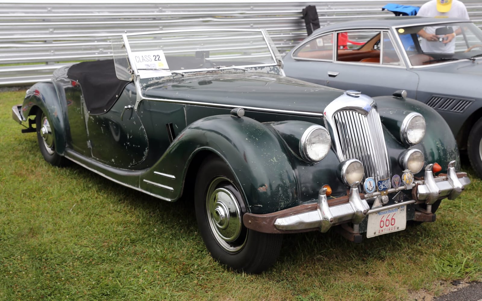 A green 1950 Riley RMC roadster with its hood down at a historic race meeting