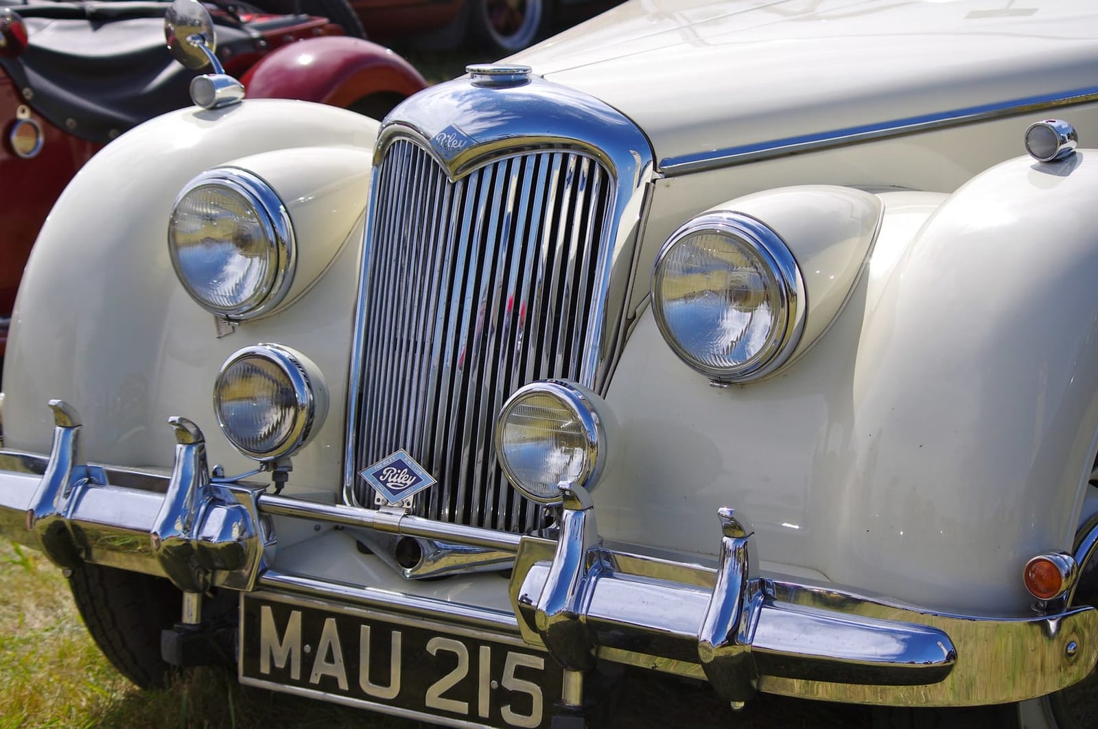 Close-up of a Riley RM radiator grille, badge and auxiliary lamps, UK registration MAU 215