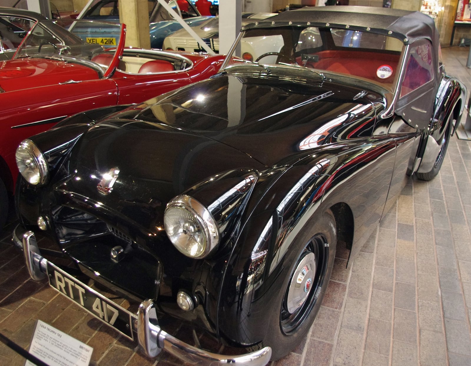 A black Triumph TR2 with a hardtop, front three-quarter view in a motor museum