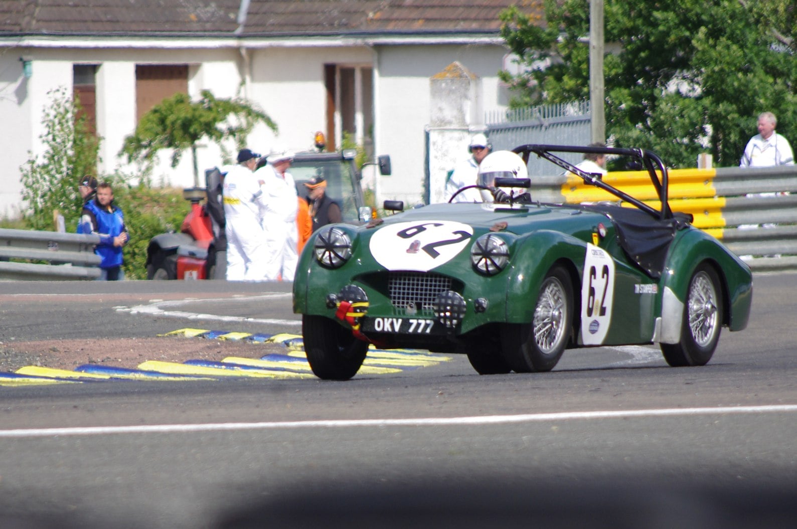 A green Triumph TR2 racing car, number 62, on the Le Mans circuit