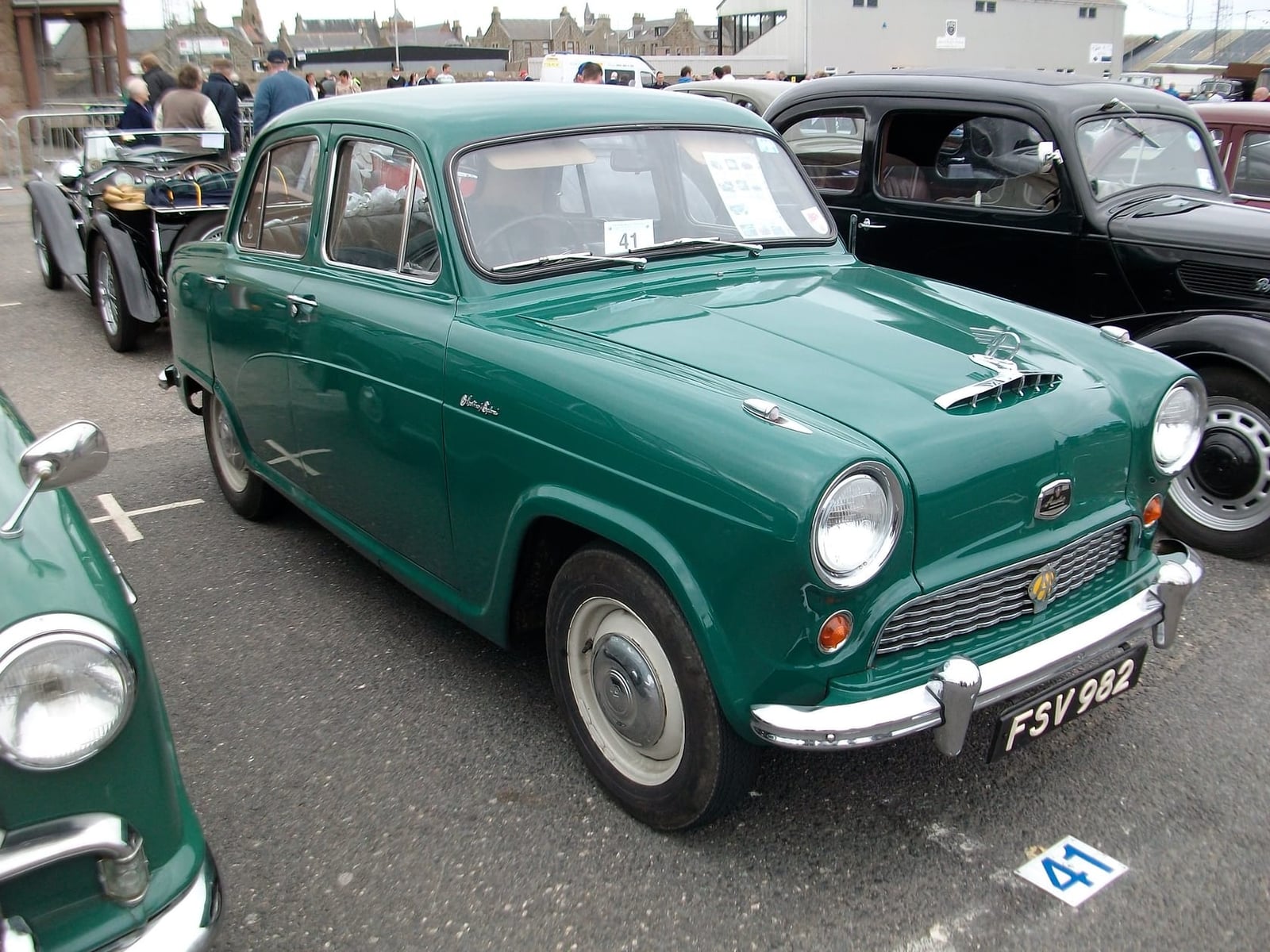 A green 1956 Austin A40 Cambridge on tarmac at a classic car show, front three-quarter view, UK registration FSV 982