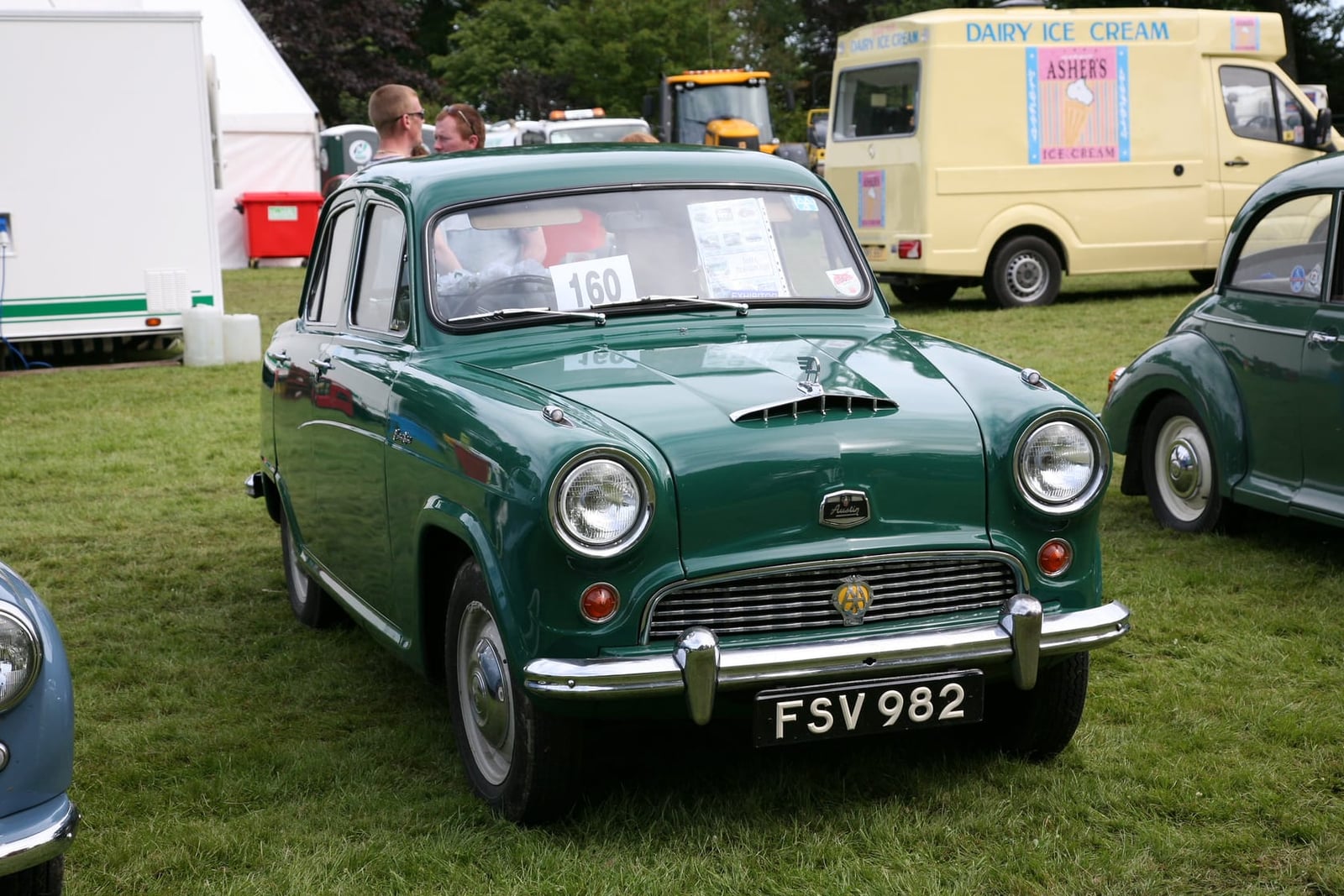 A green 1956 Austin A40 Cambridge saloon at a showfield, front three-quarter view, UK registration FSV 982