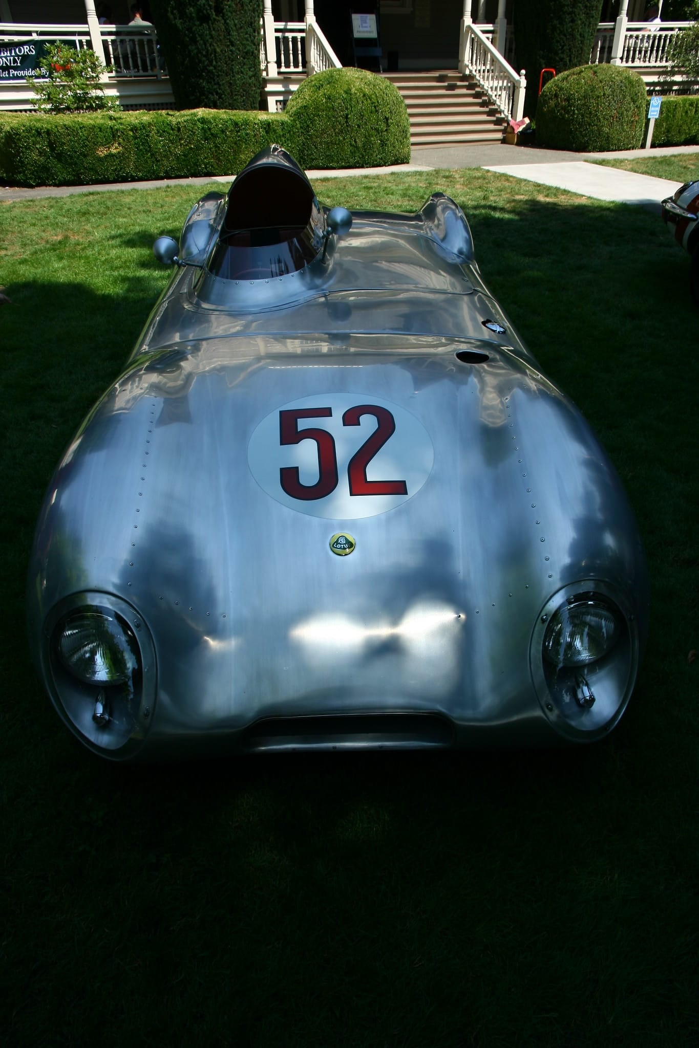 A bare-aluminium 1956 Lotus Eleven Le Mans race car numbered 52, seen from above and behind