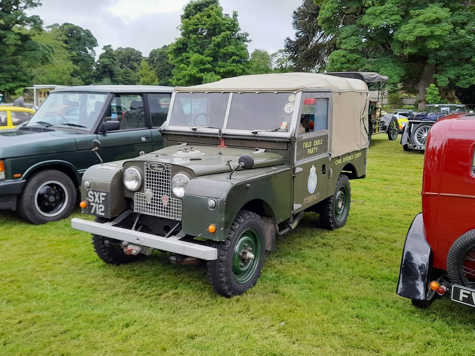 A military green 1958 Land Rover Series I with a canvas tilt and a UK registration among classics at a show